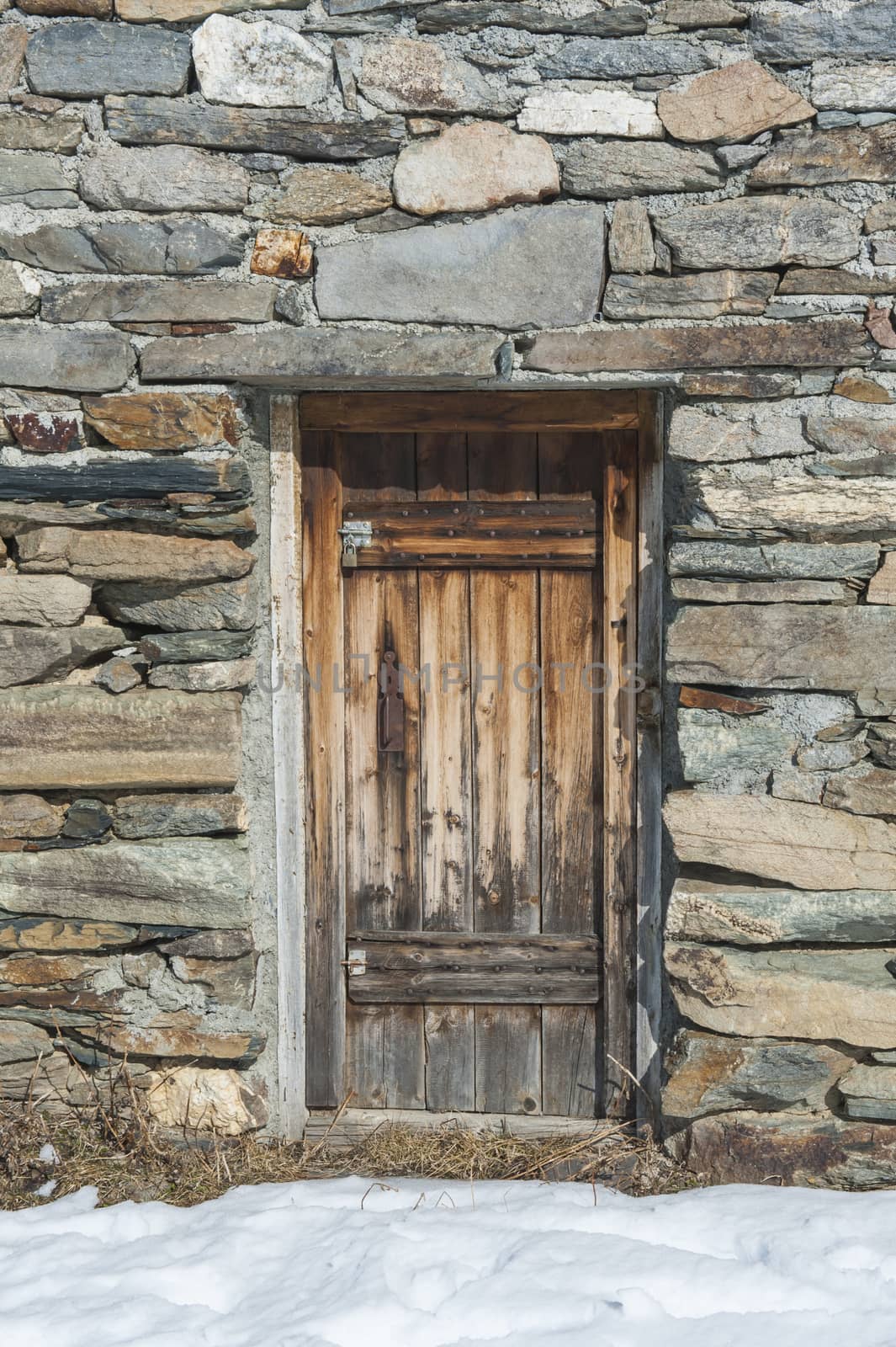 Wooden doorway of remote stone mountain hut on an alpine slope covered in snow