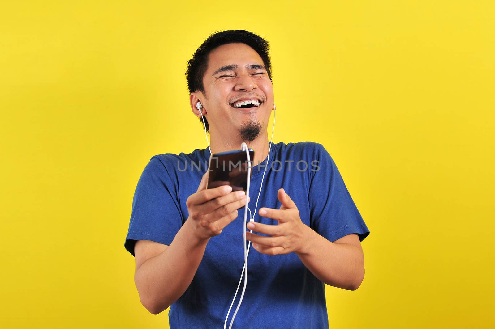 Portrait of excited Asian man laugh happily listening of music f by heruan1507