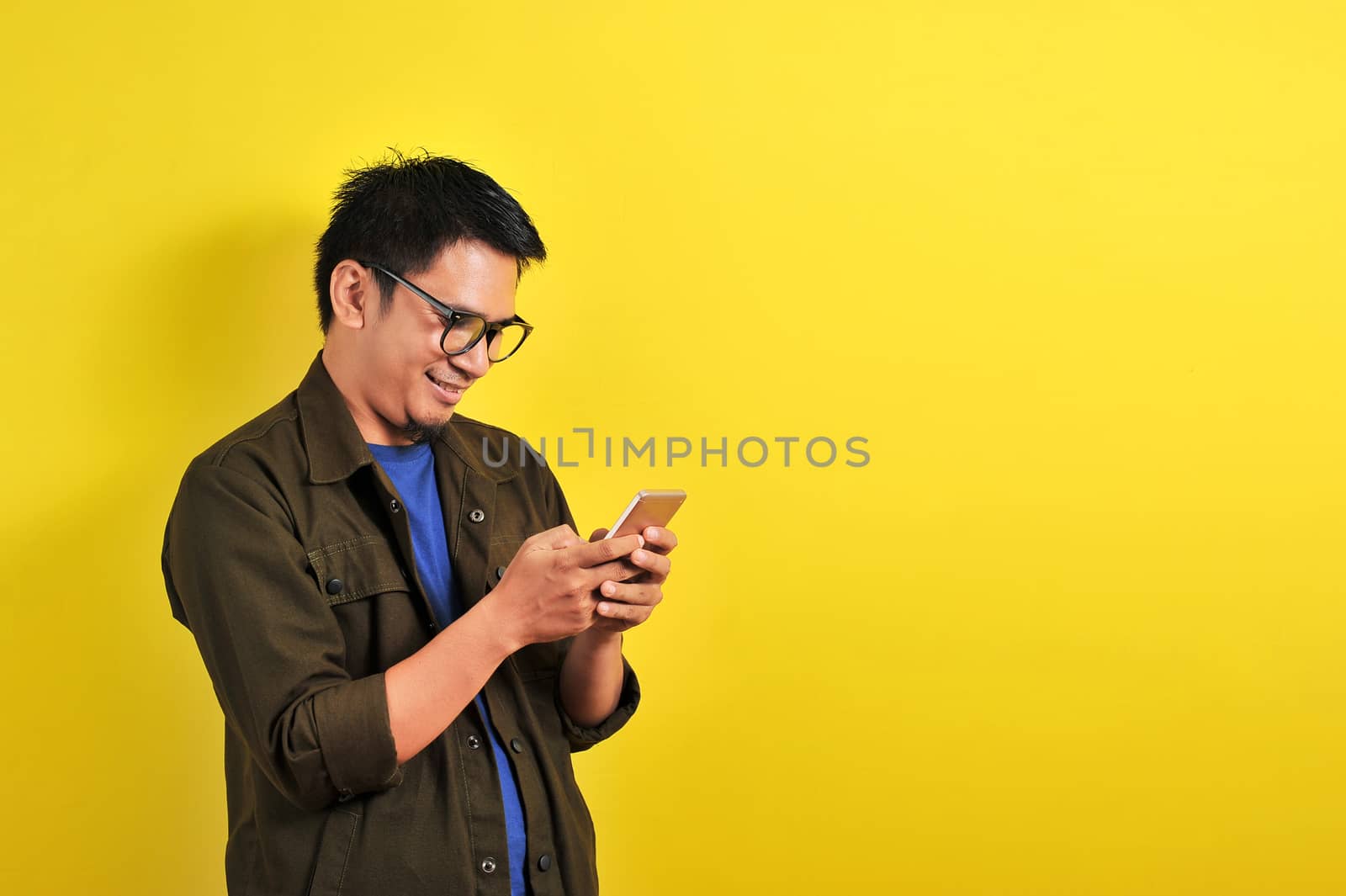 Portrait of happy smiling Asian man using smartphone by heruan1507