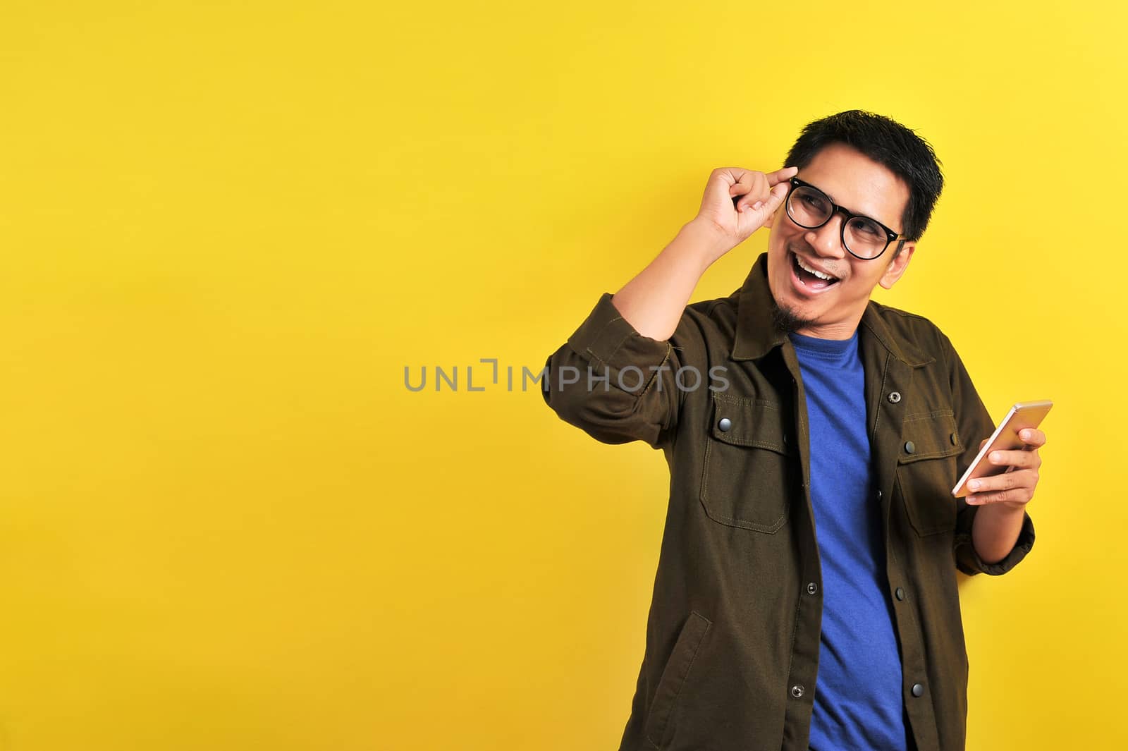 Portrait of happy smiling Asian man using smartphone wearing casual t-shirt and jacket with eyesglasses, get the best price, using simple mobile banking payment