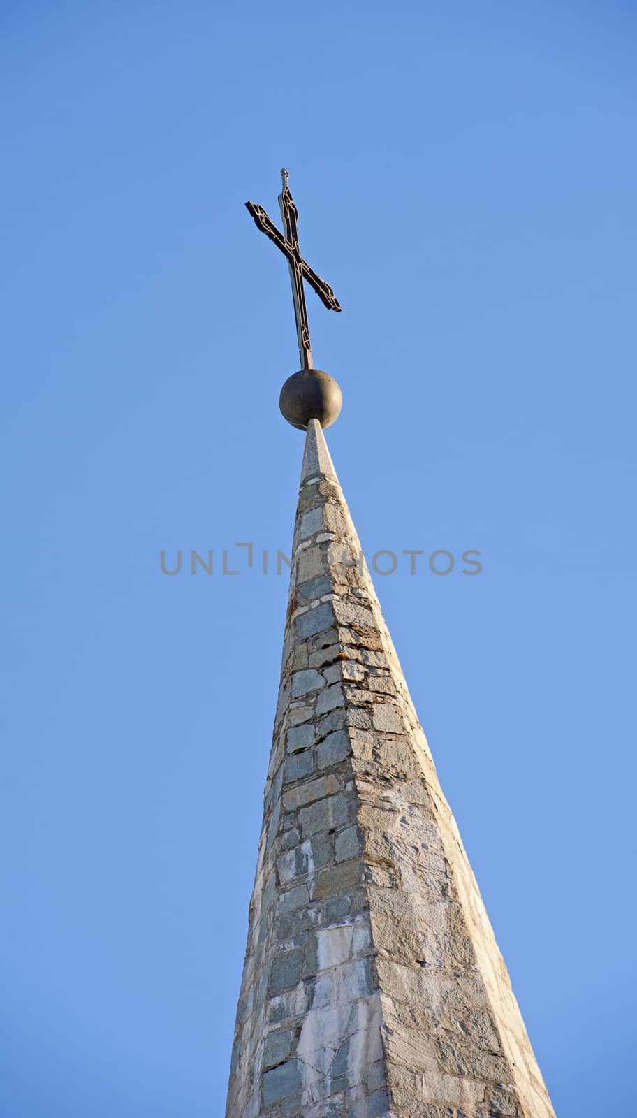 Top of a church steeple with cross against blue sky background