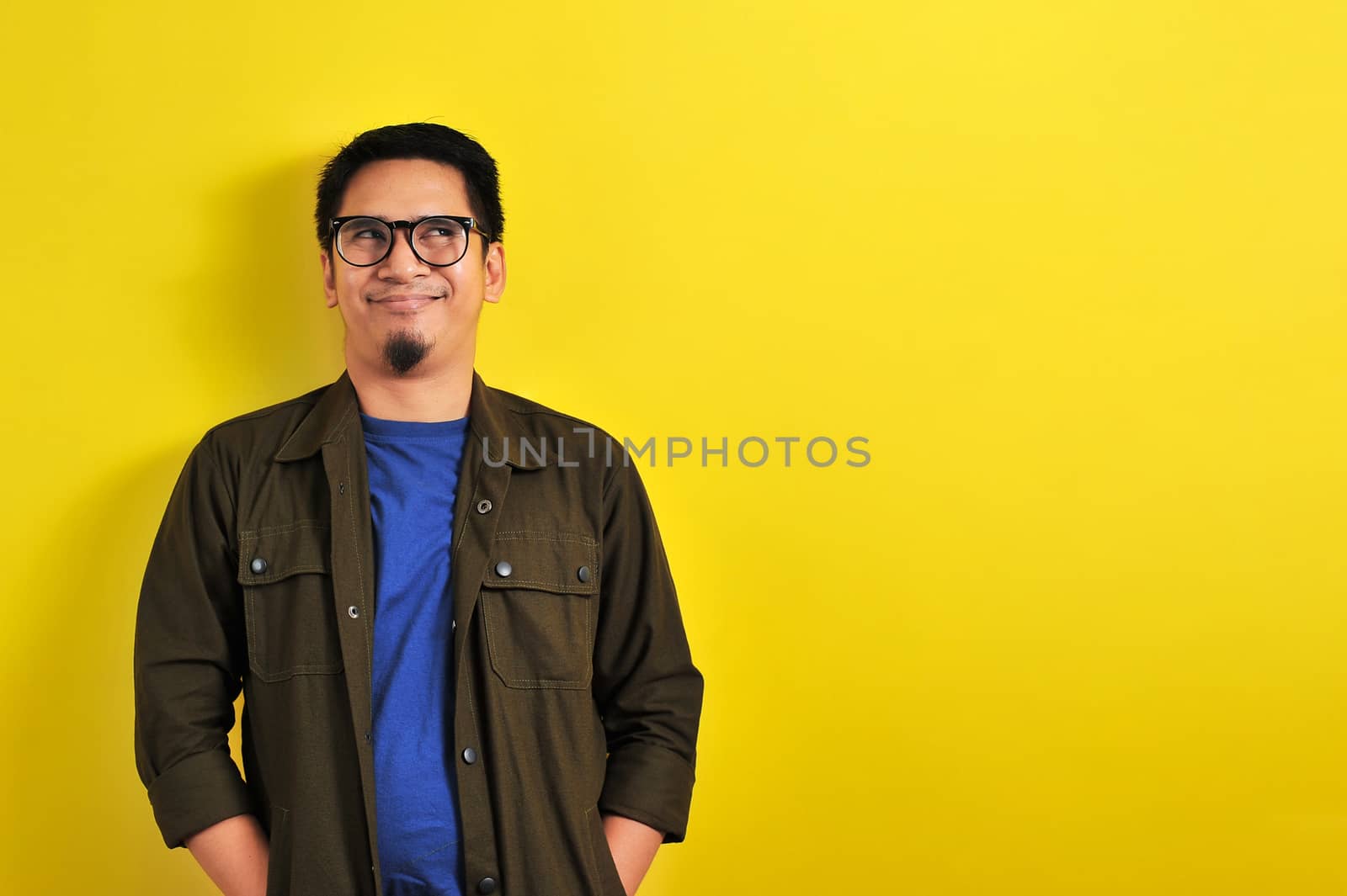 Asian Man with humorist face or funny face look at copy space, isolated on yellow background