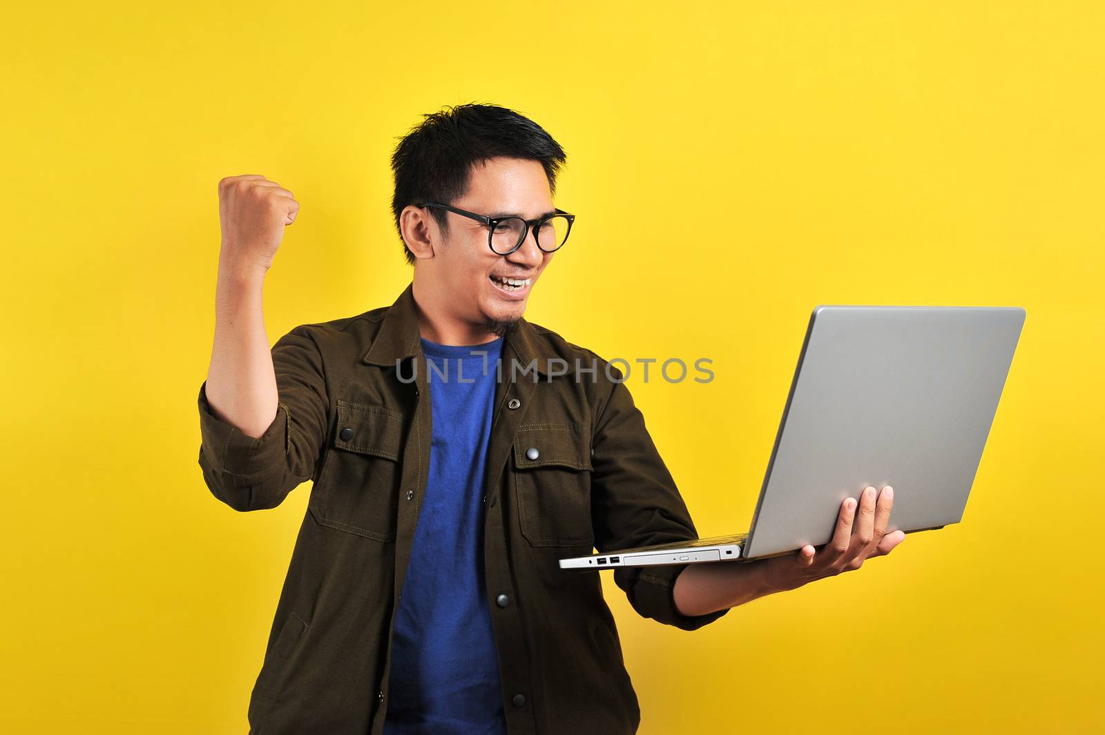 Asian man holding laptop with winning gesture, winning gift by heruan1507