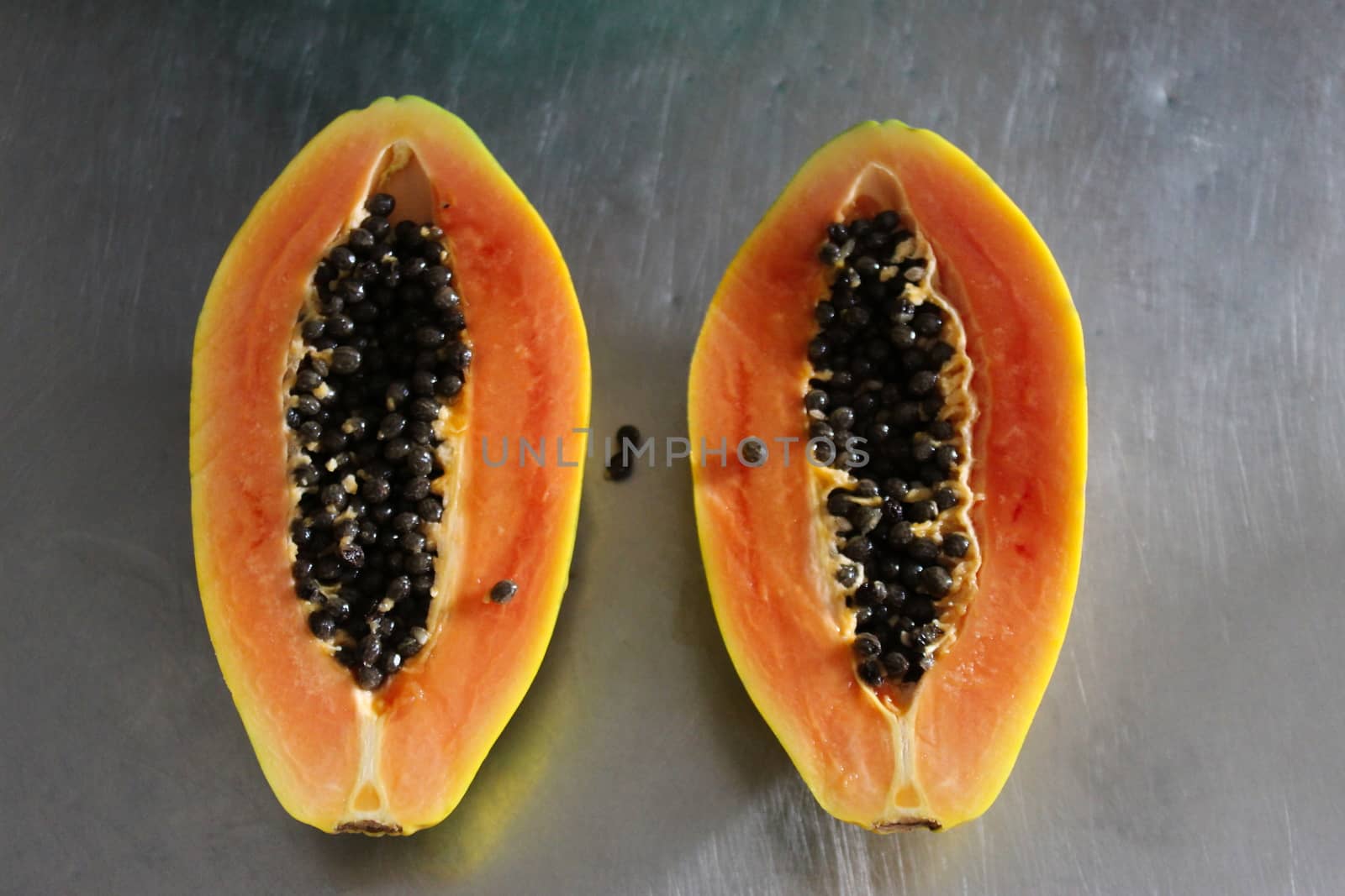 Two halves of papaya fruit on the kitchen table. Papaya fruit with black seeds.