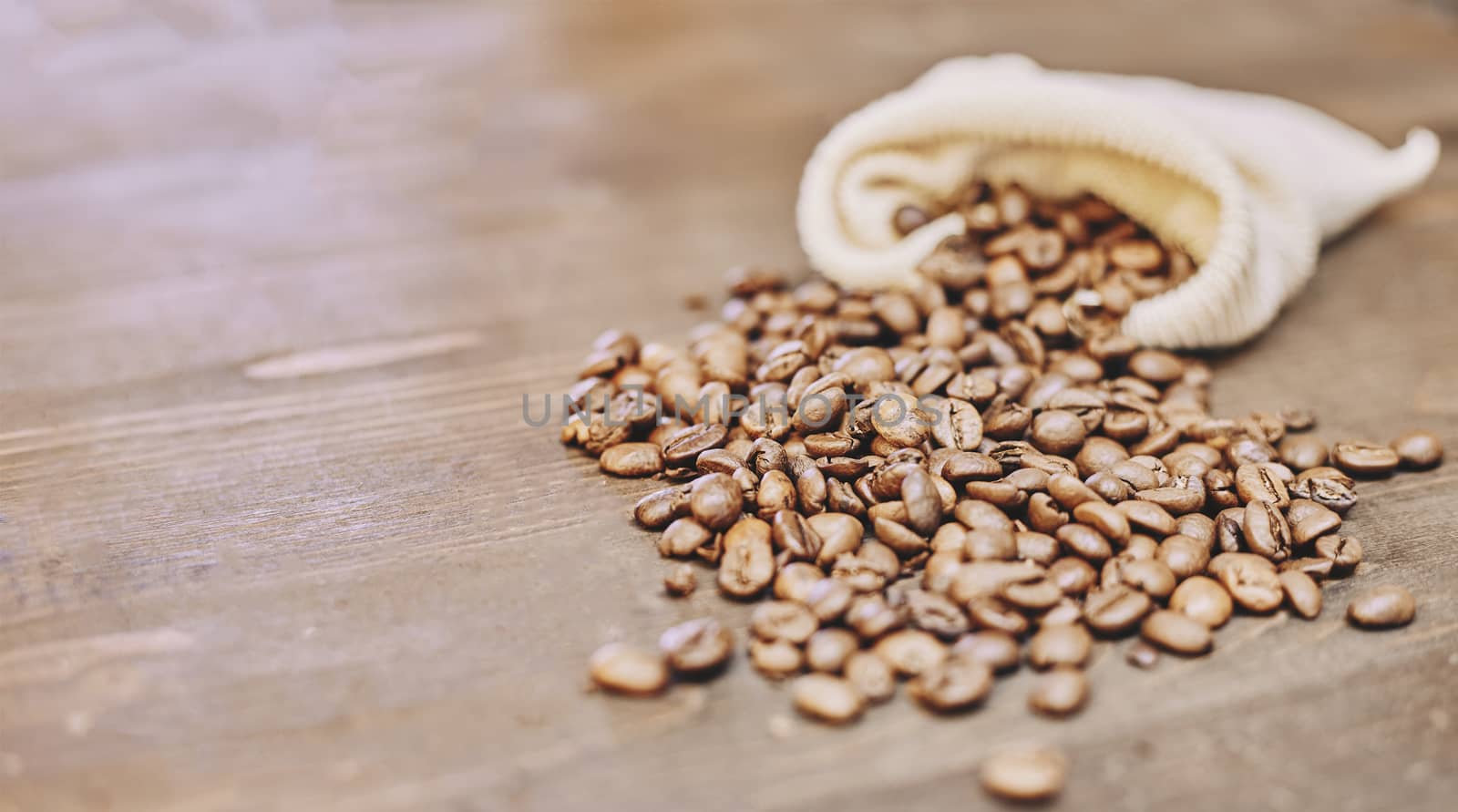 Coffee beans coming out of a sack on a wooden table