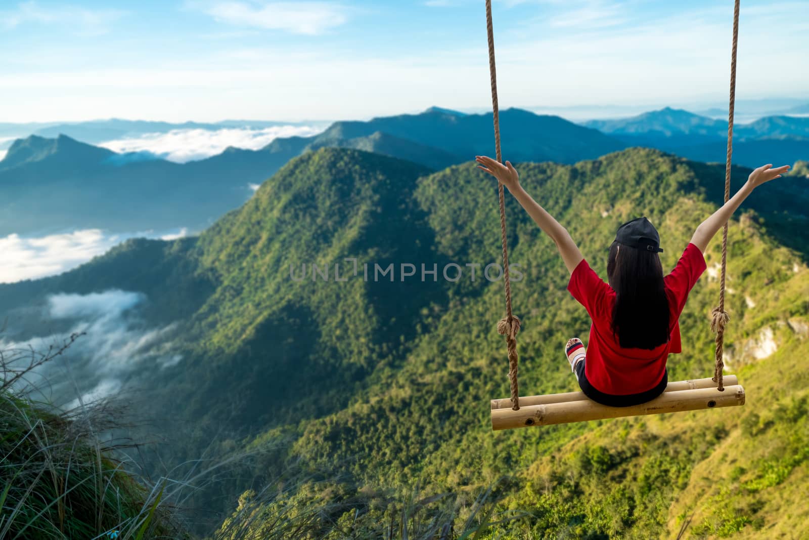 Female tourists sit and swing on the top of the high hill