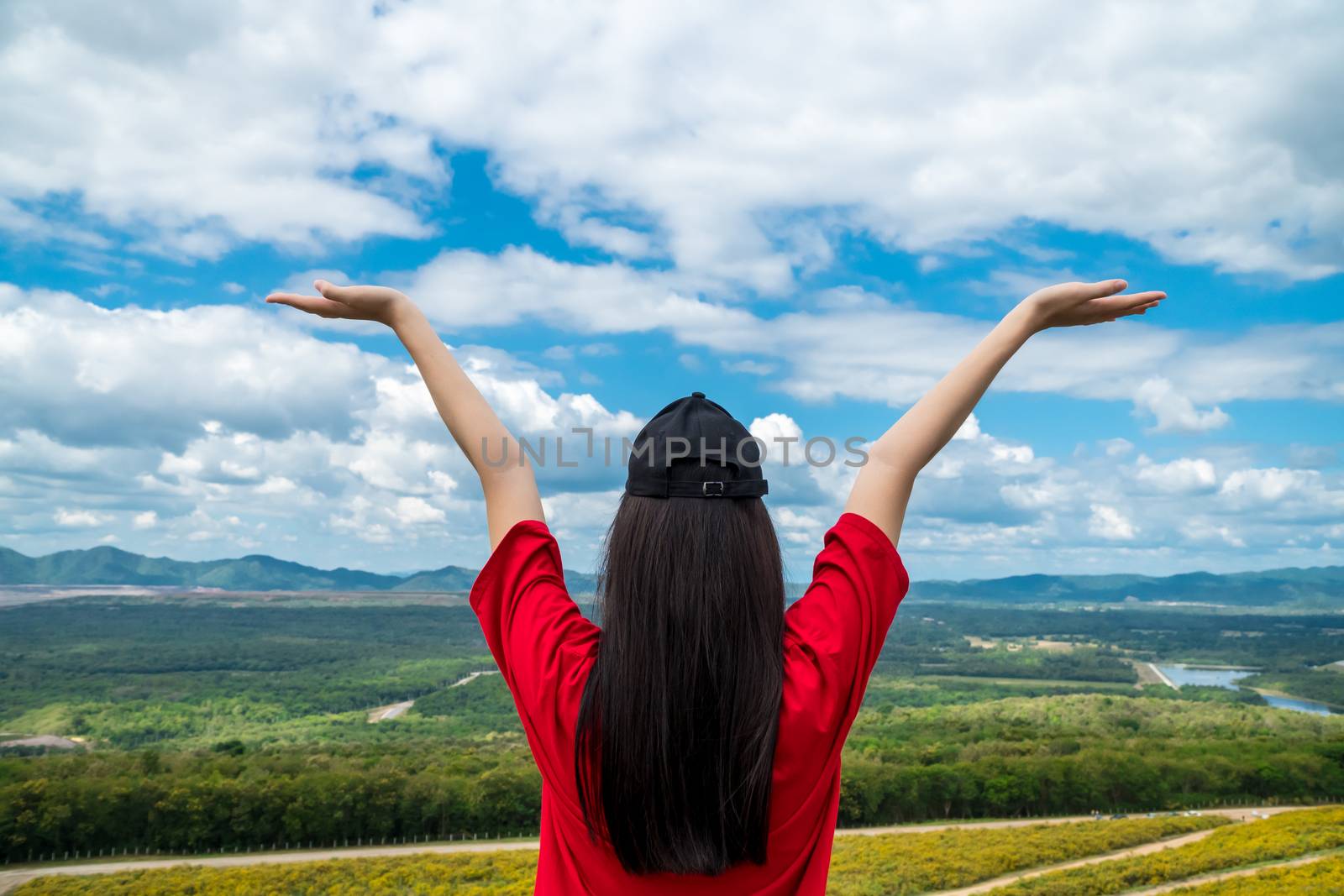 Happy female tourists hands up on the top of the high hill