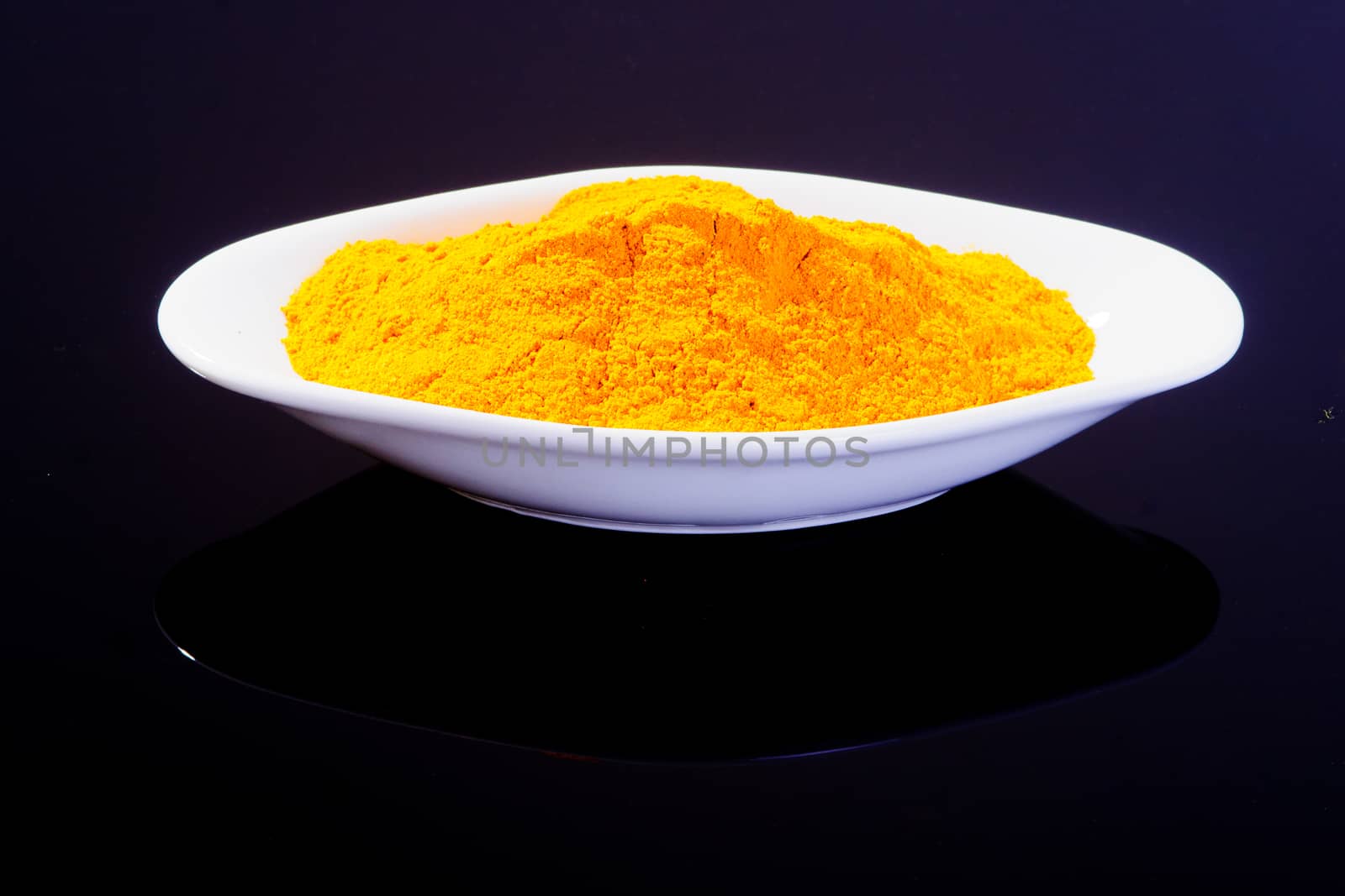 Turmeric in a white plate on black background