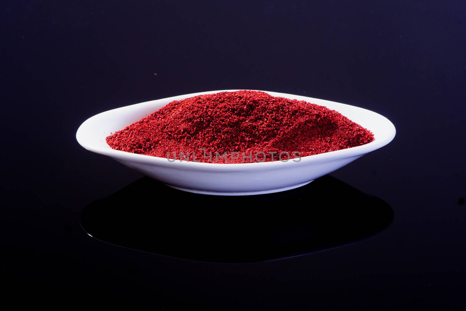 Sumac in a white plate on black background