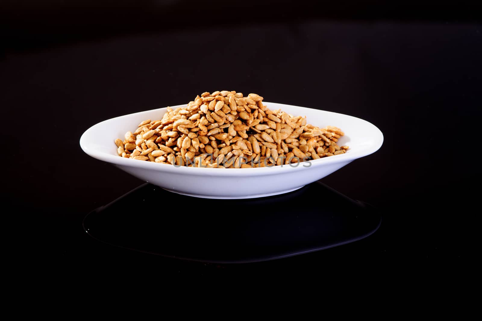 Roasted Salted Sunflower Seeds in a white plate on a black background