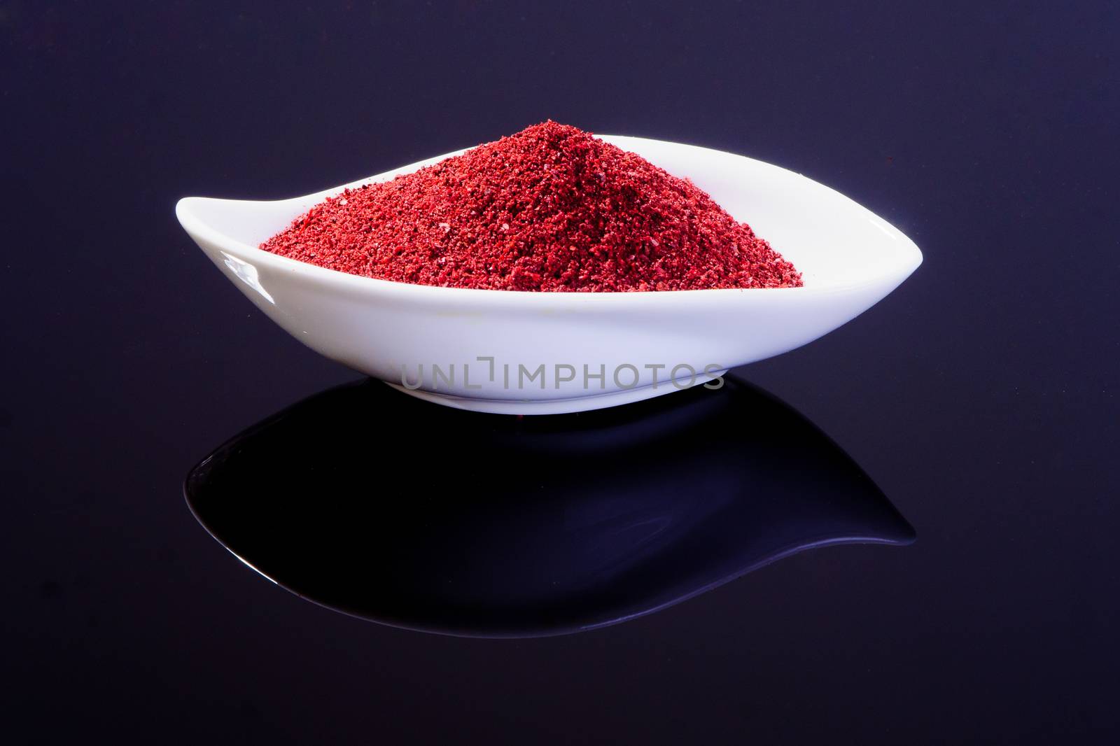 Sumac in a white plate on black background