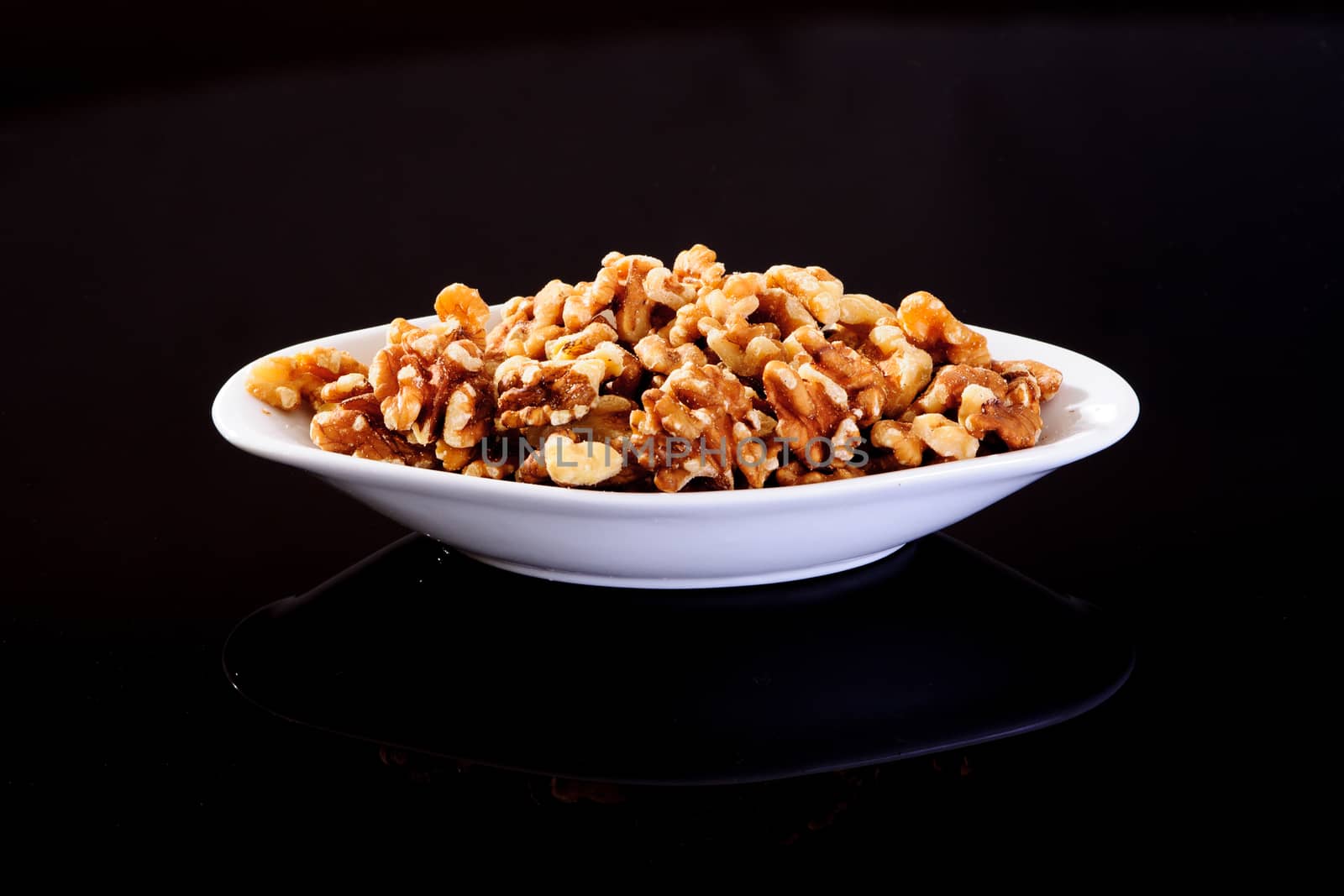 California Walnuts in a white plate on a black background