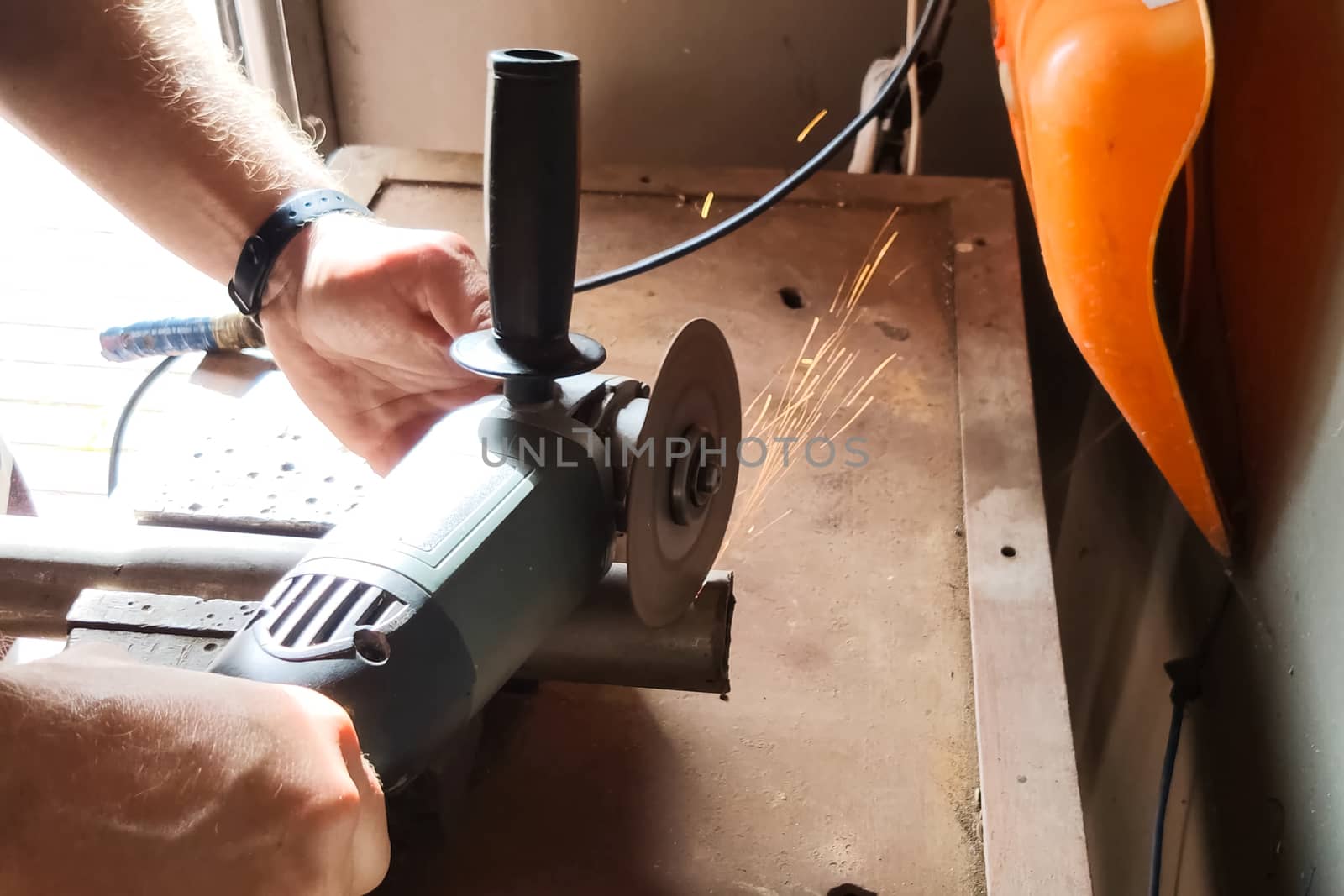 a Worker cuts off piece of pipe with grinder