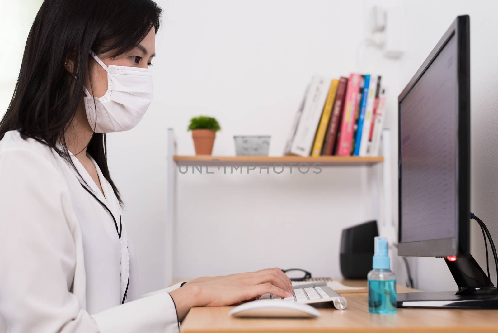 A beautiful Asian businesswoman wearing a mask and cleaner gel t by animagesdesign