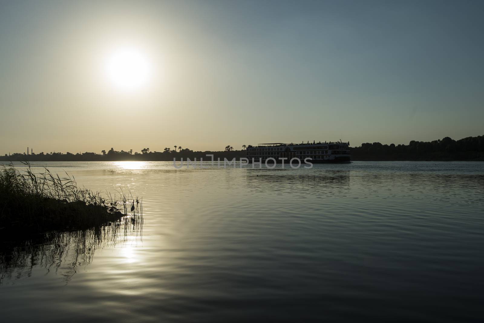 Large luxury traditional Egyptian river cruise boat sailing on the Nile with sunset in background