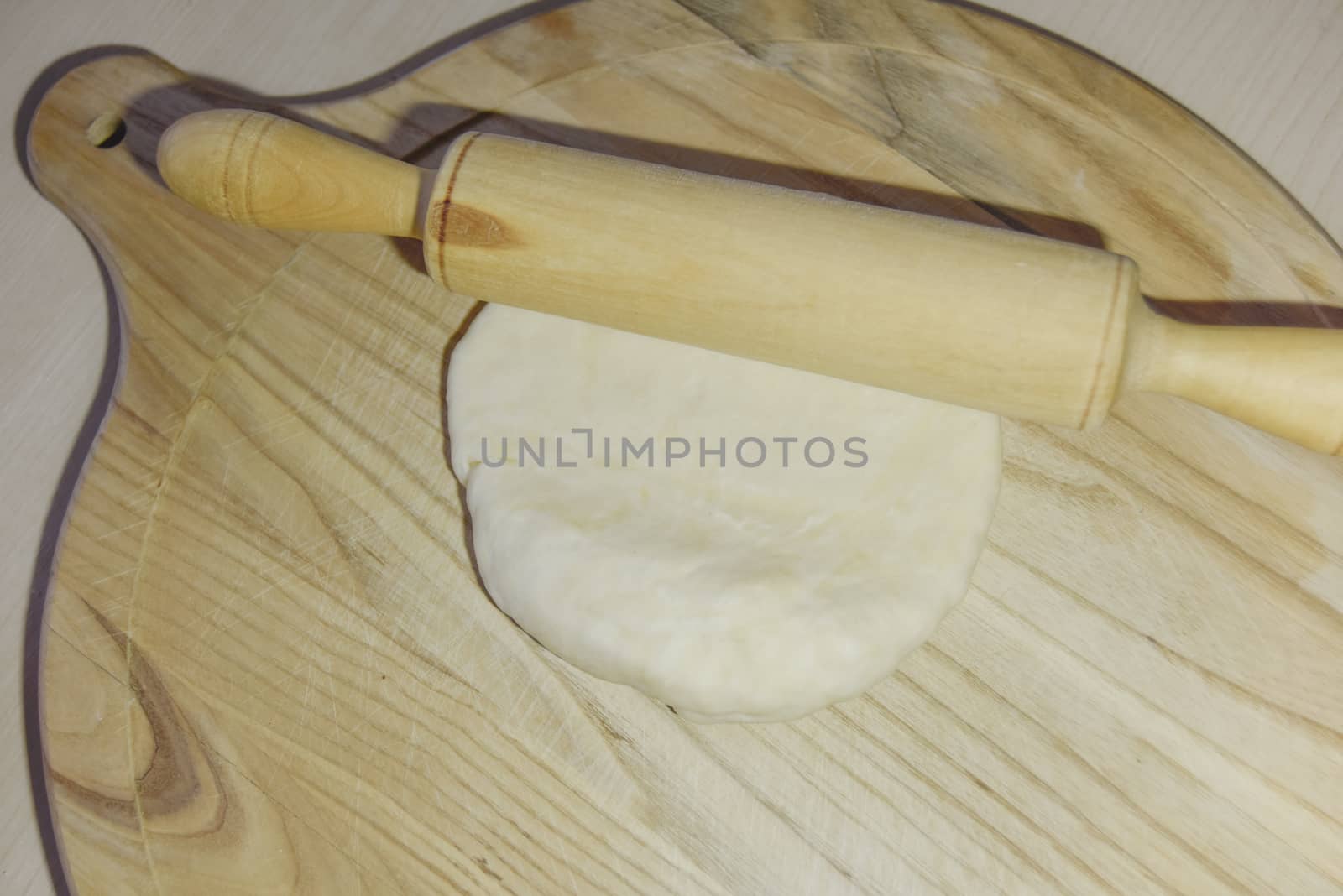 selective focus at the dough and roller at the wooden chopping board