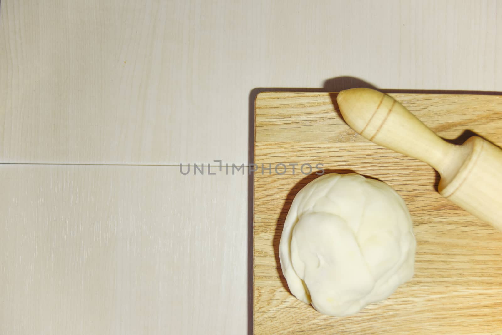 focus on the wooden chopping board and blury dough and roller. cooking concept