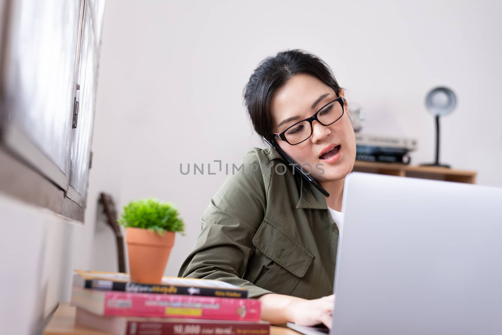 Modern young Asian woman working from home and talking with a partner about her business.