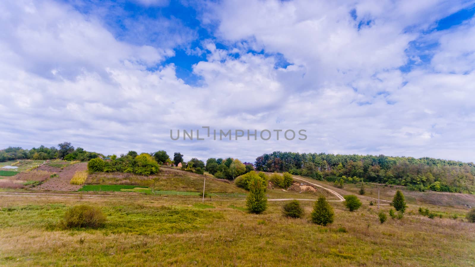 Aerial view of the landscape: hills, trees and blue sky with white clouds.