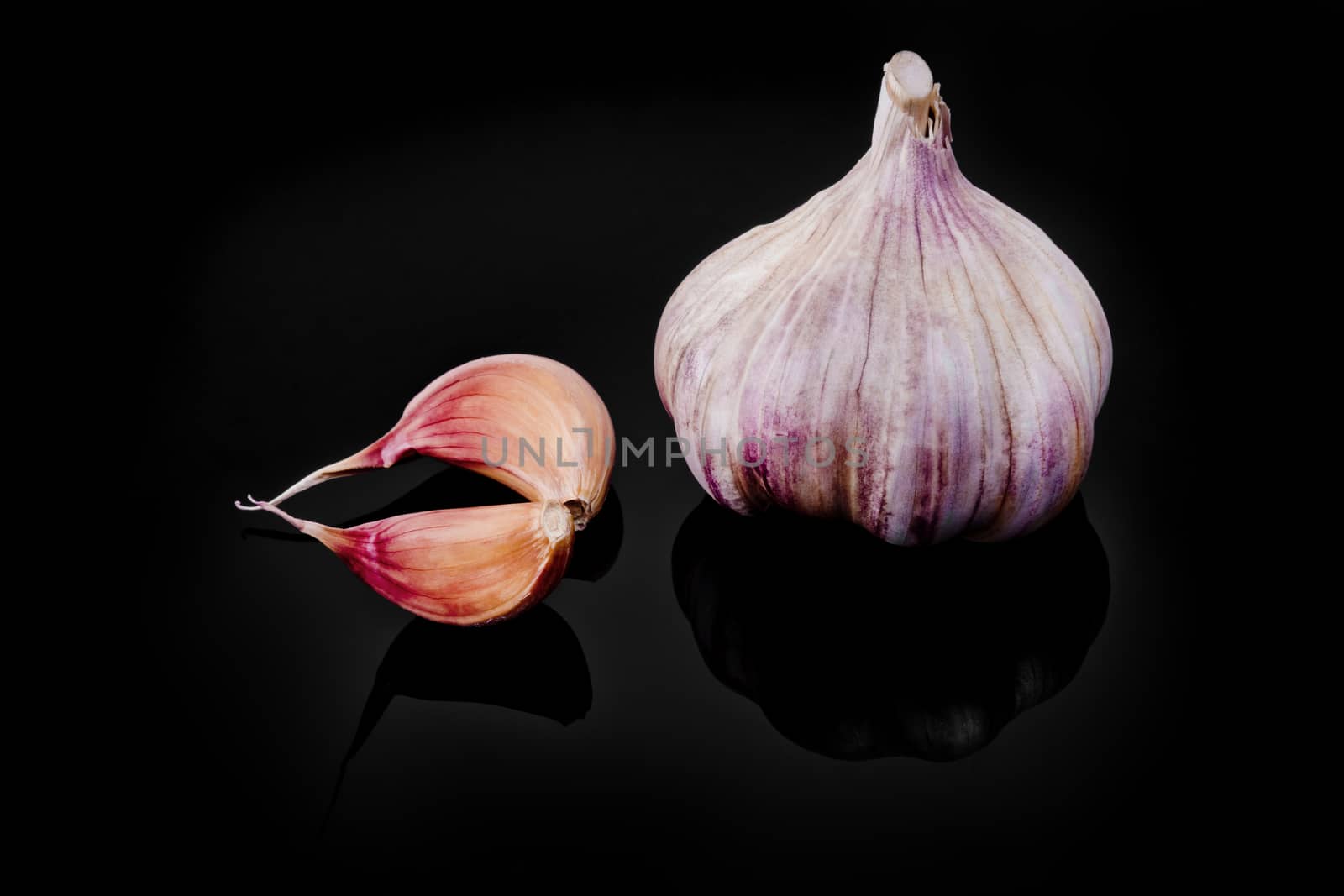 Close-up of garlic with reflection on black background.