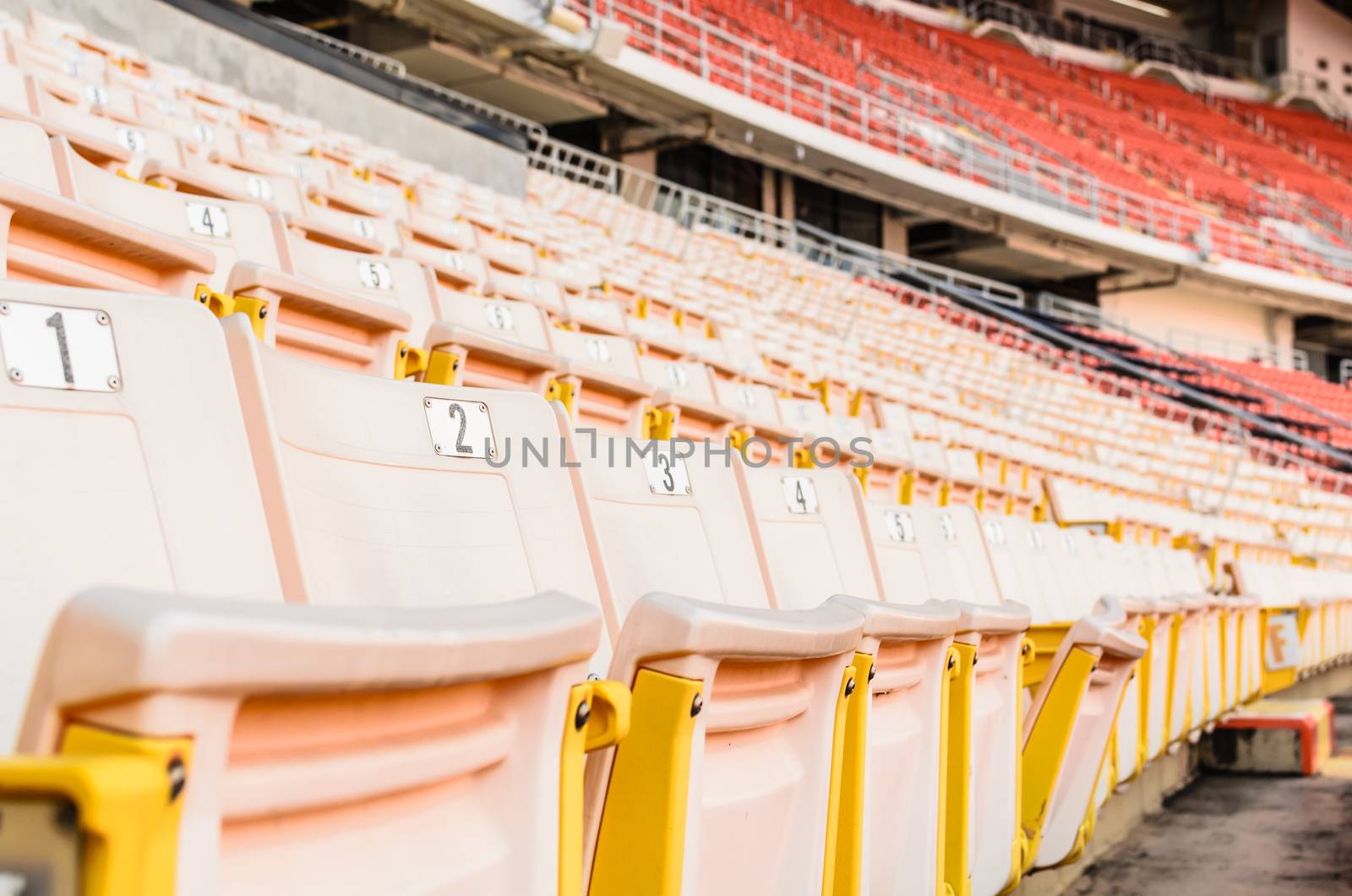 A lot of Light Orange Seat at football stadium in the morning.