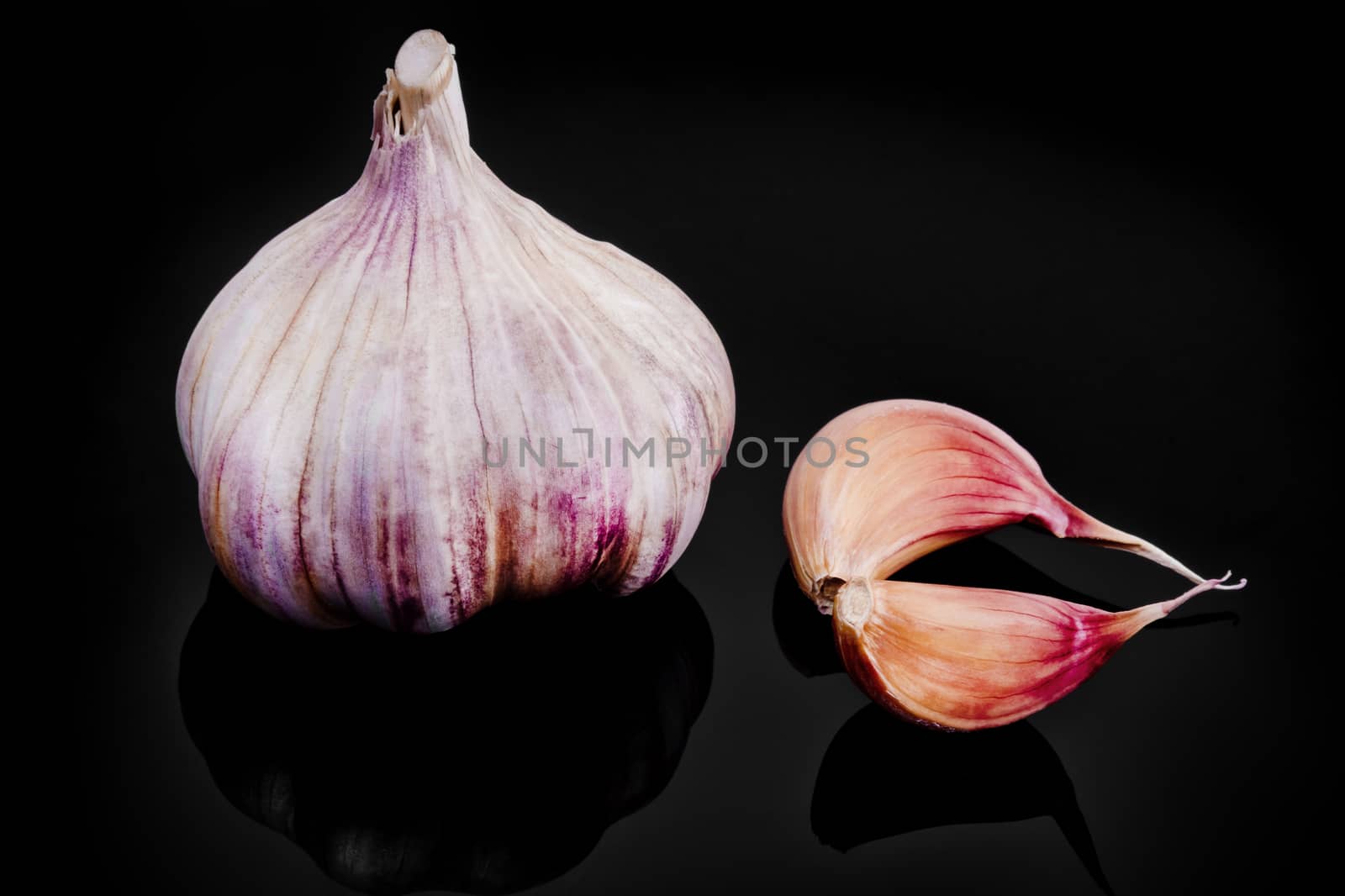 Close-up of garlic with reflection on black background.