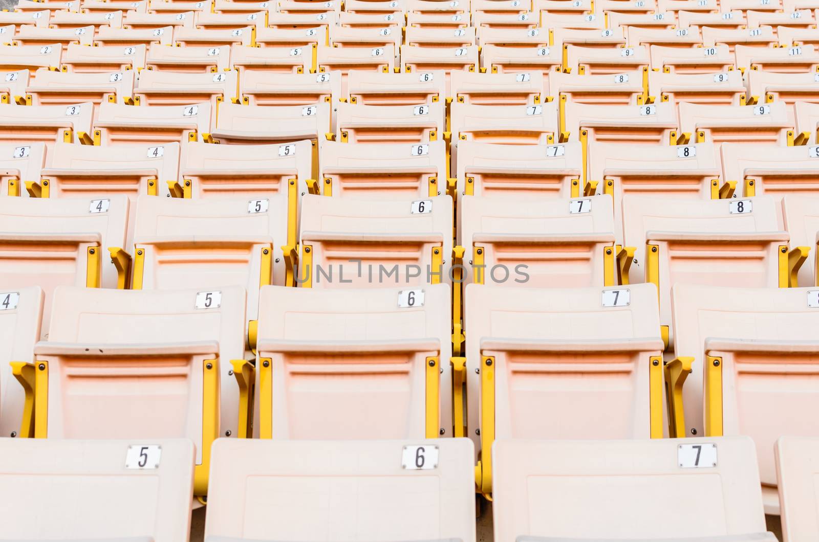 A lot of Light Orange Seat at football stadium in the morning.