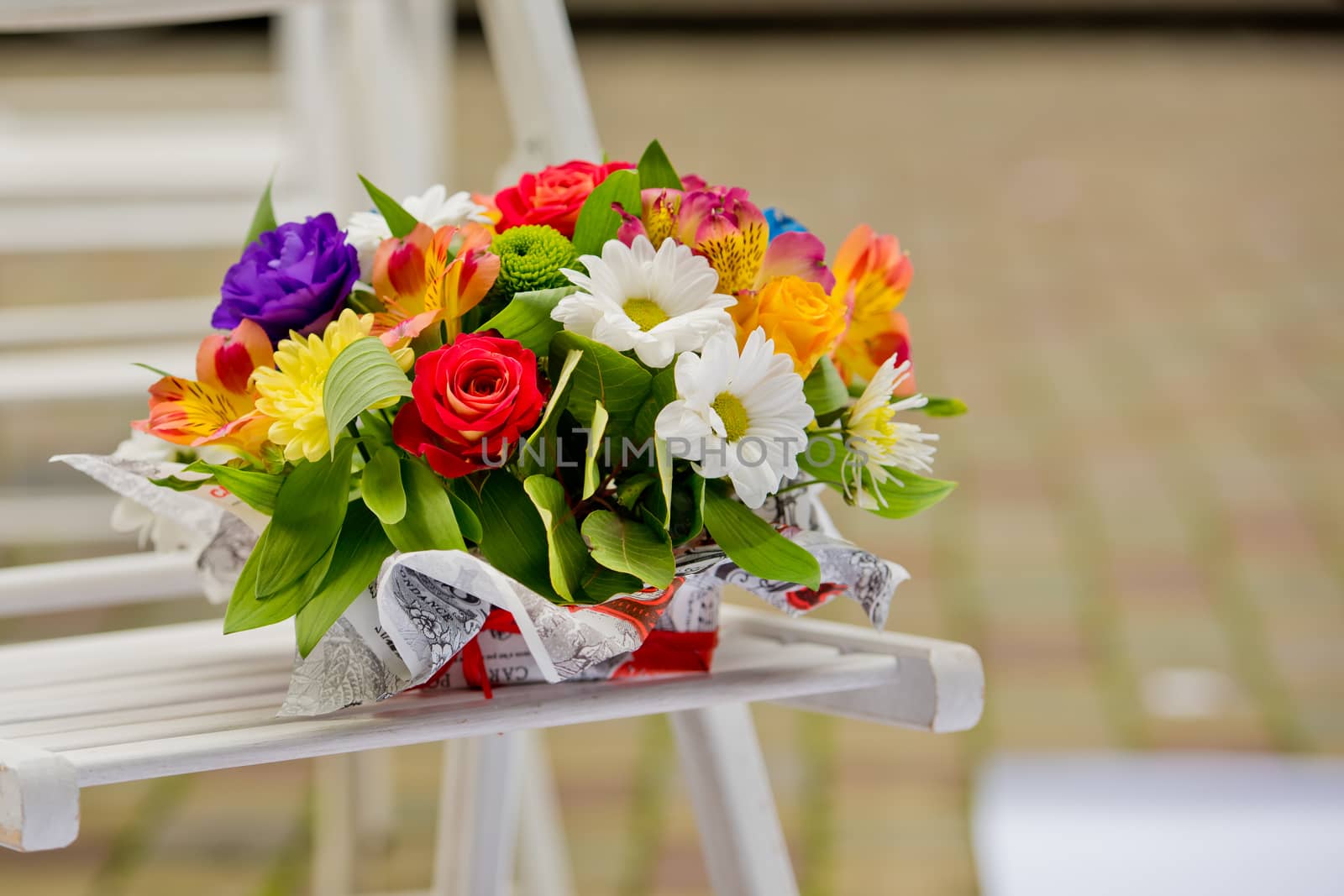 A beautiful gift bouquet in a wooden vase on a wooden bench. Wedding decorations.