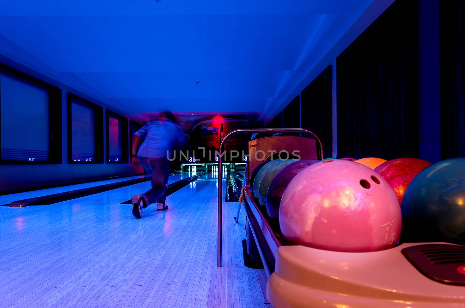 A Pink Bowling balls has ready for player to throwing ball on the wooden lane and in the bowling hall.