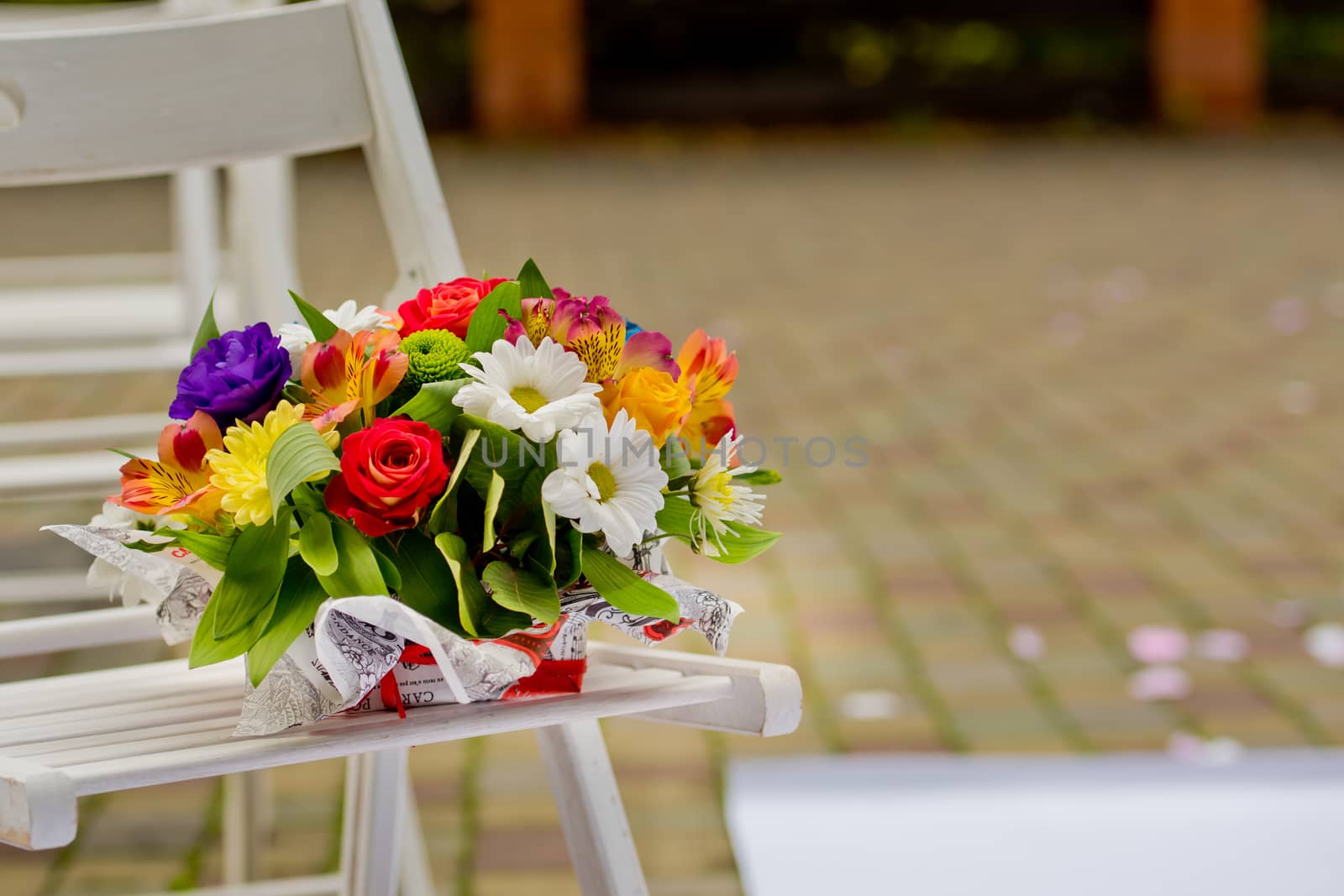 A beautiful gift bouquet in a wooden vase on a wooden bench. Wedding decorations.
