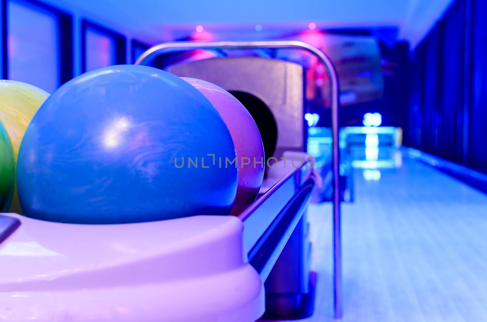 A Purple Bowling balls has ready for player to throwing ball on the wooden lane and in the bowling hall.