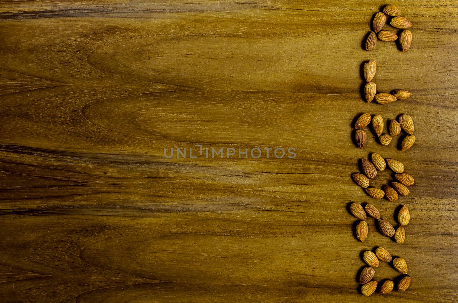 The word is Almonds on the wood table background.