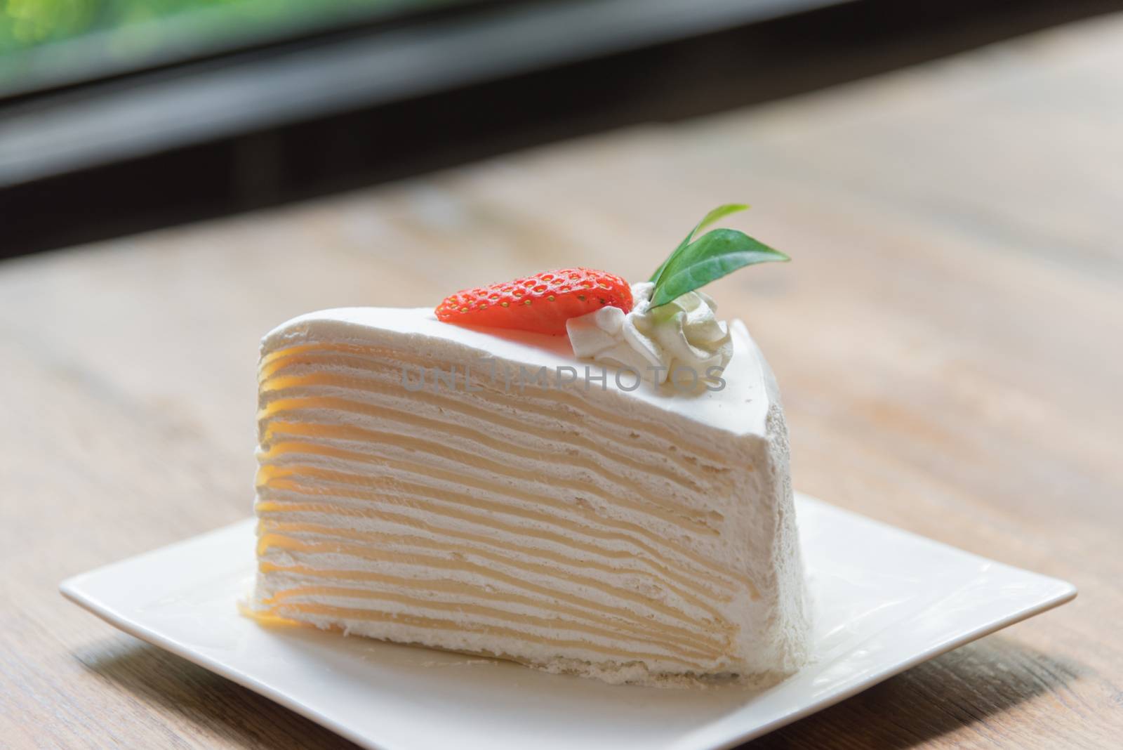 Strawberry crape cake in white plate with closeup view on wooden and ready to served in the morning.