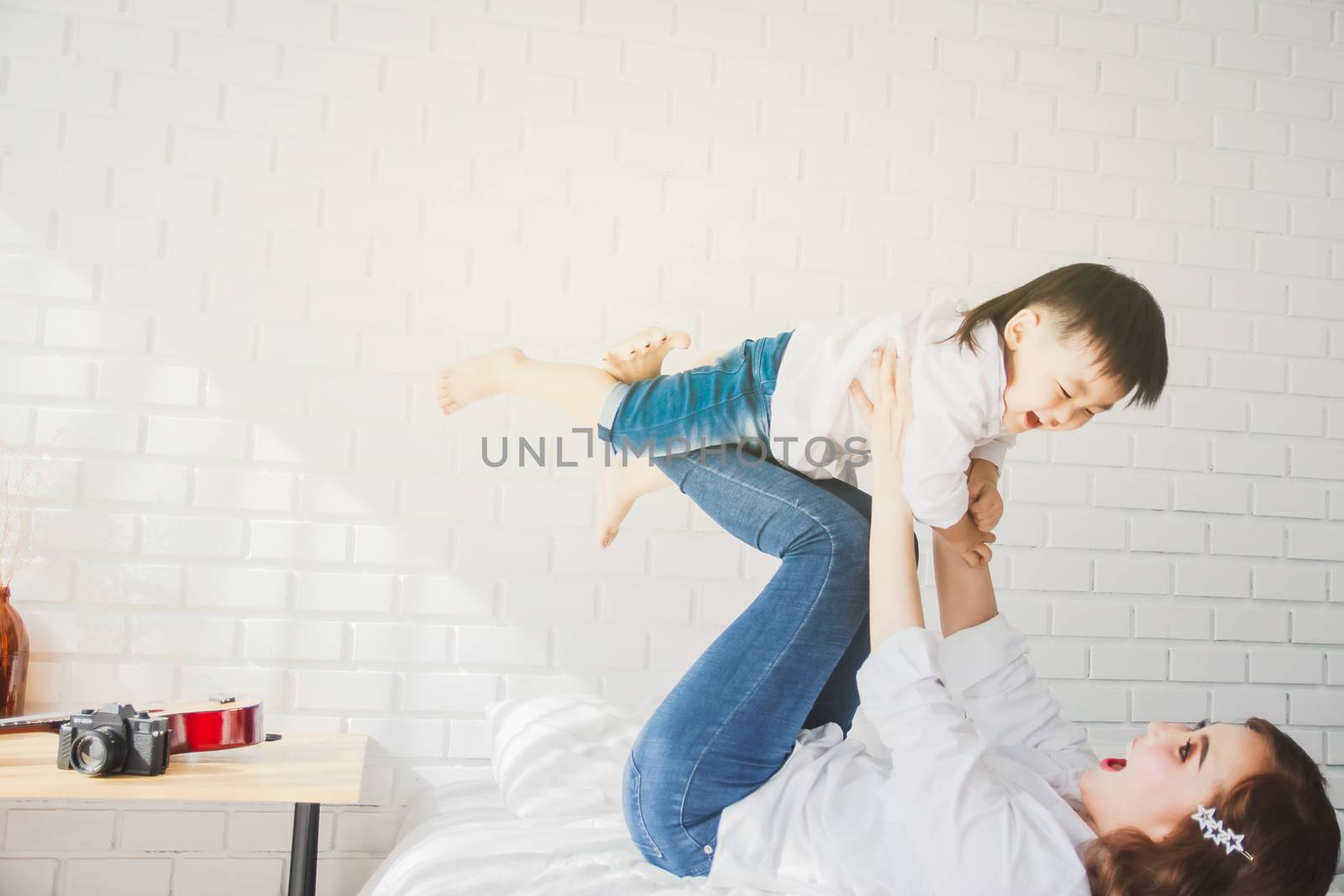 Asian Japanese Family father mother son wearing white shirt carrying child posing for photo on bedroom in white room.To keep memories moment cuteness of son in childhood lifestyle happy