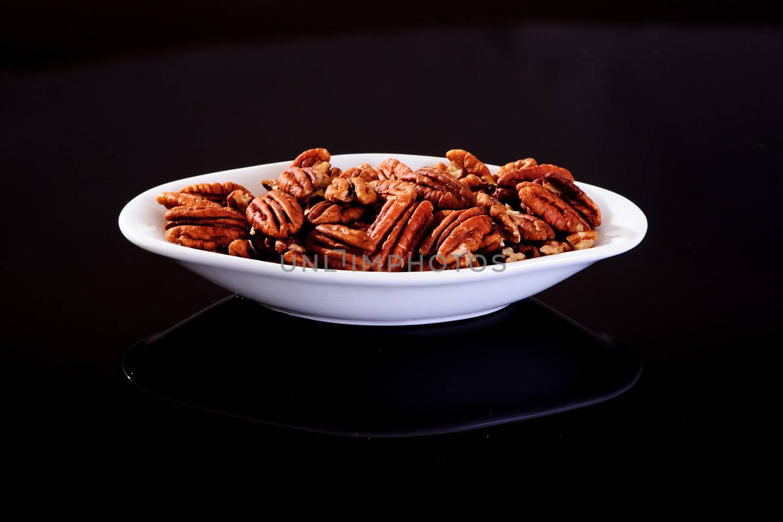 Pecan Nuts in a white plate on a black background