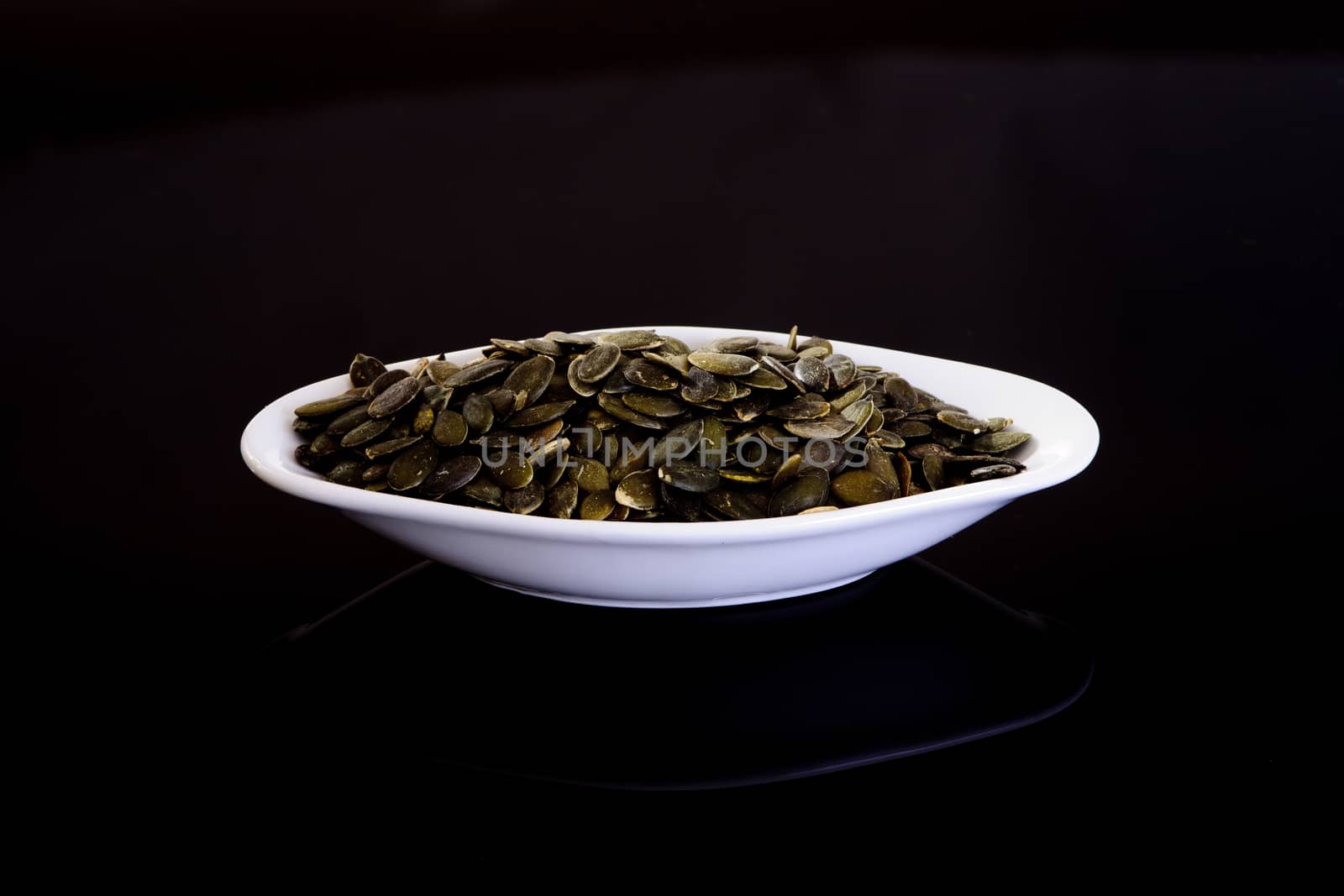 Pumpkin Seeds in a white plate on a black background