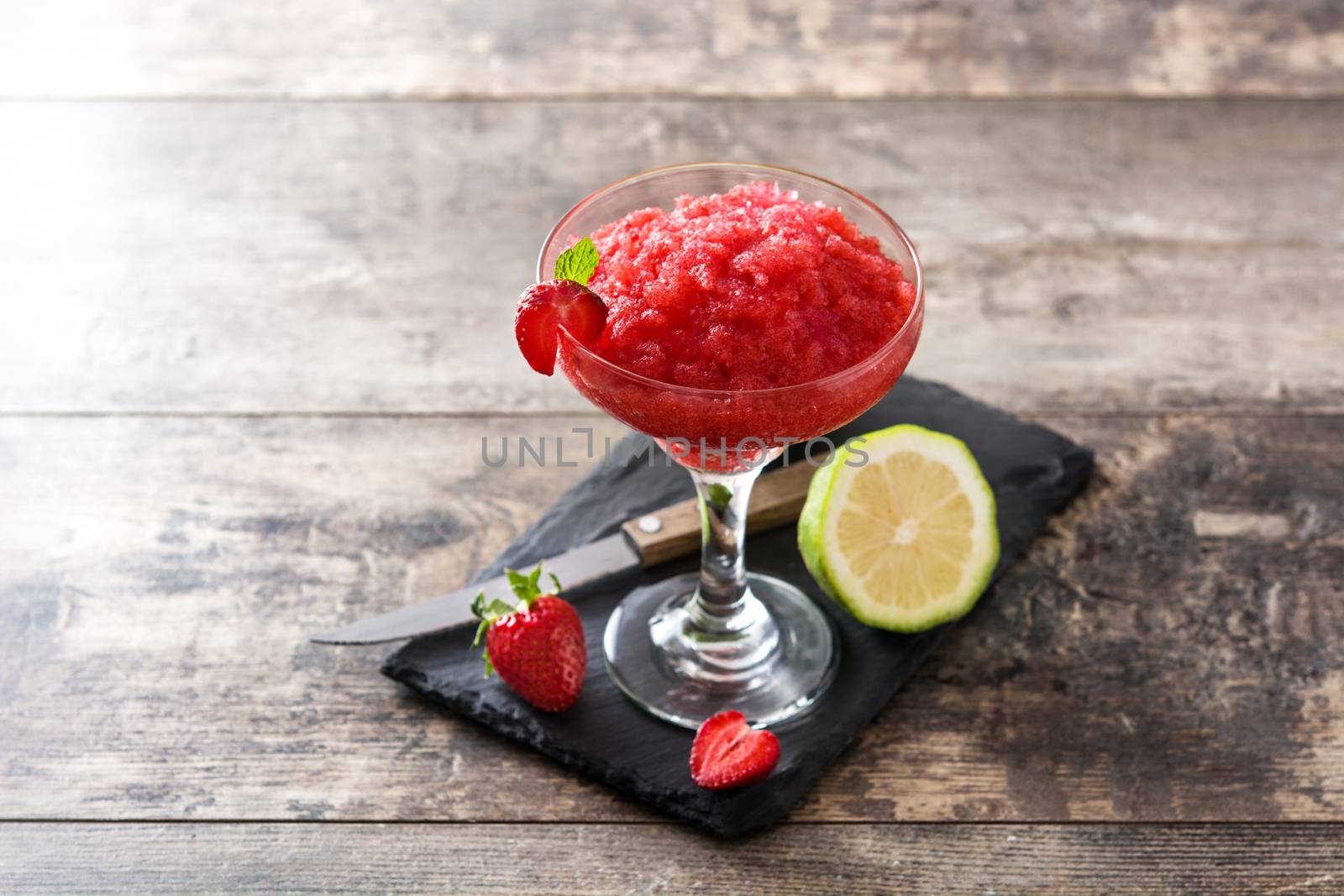 Strawberry margarita cocktail in glass on wooden table