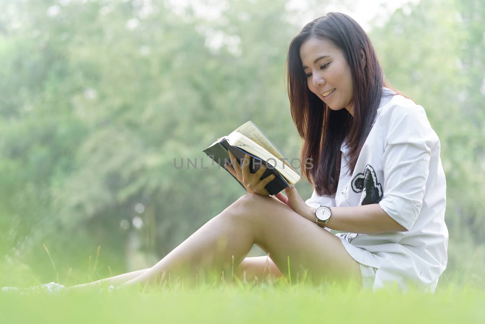 Beautiful asian woman reading a book at garden with happiness and relaxing in the evening with sunset time.