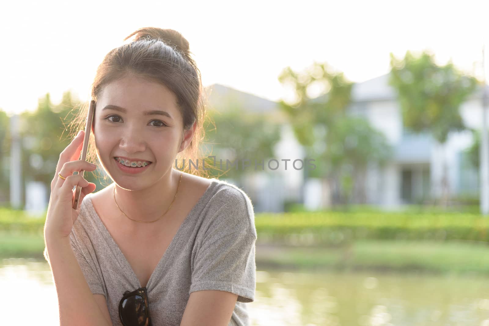 A beautiful tourist woman has playing phone in the evening with sunset time at garden park and river.