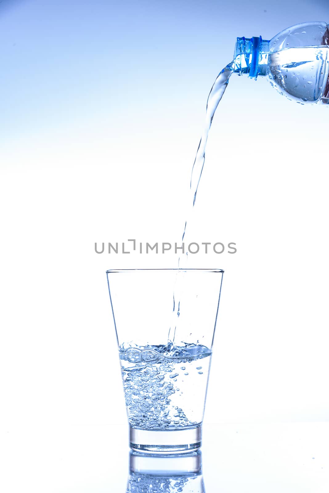 Pouring water and splashing in the glass with reflection on mirror.