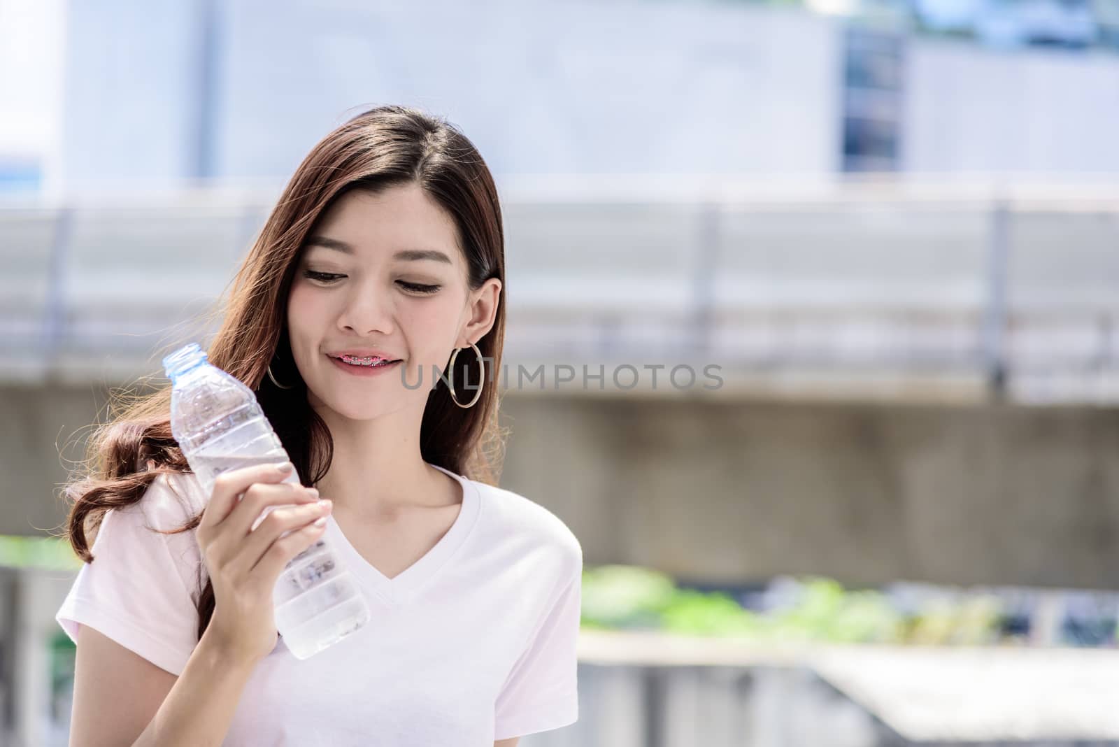 Asian beautiful woman has water drinking with city background in by animagesdesign