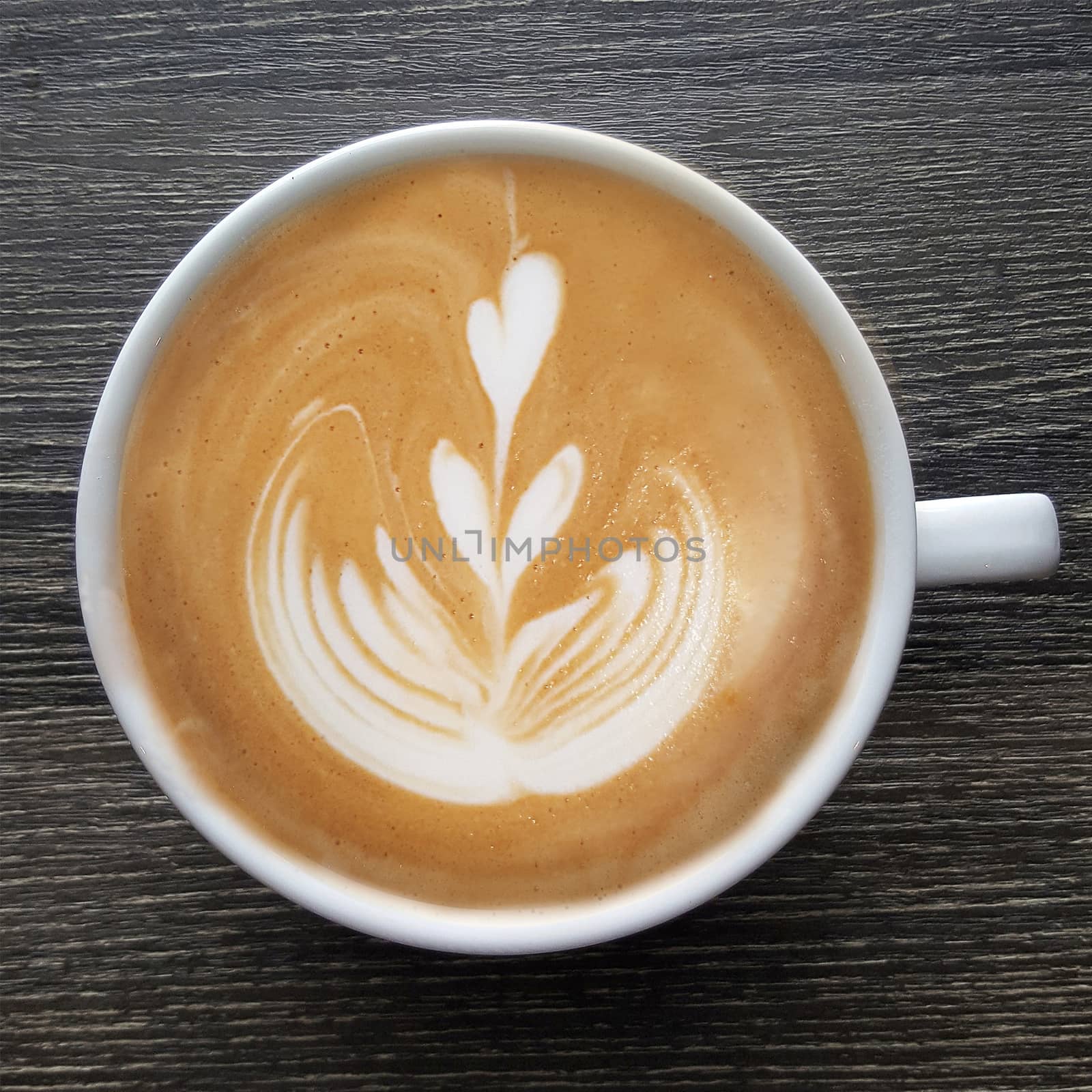 Top view of a mug of latte art coffee on timber background.