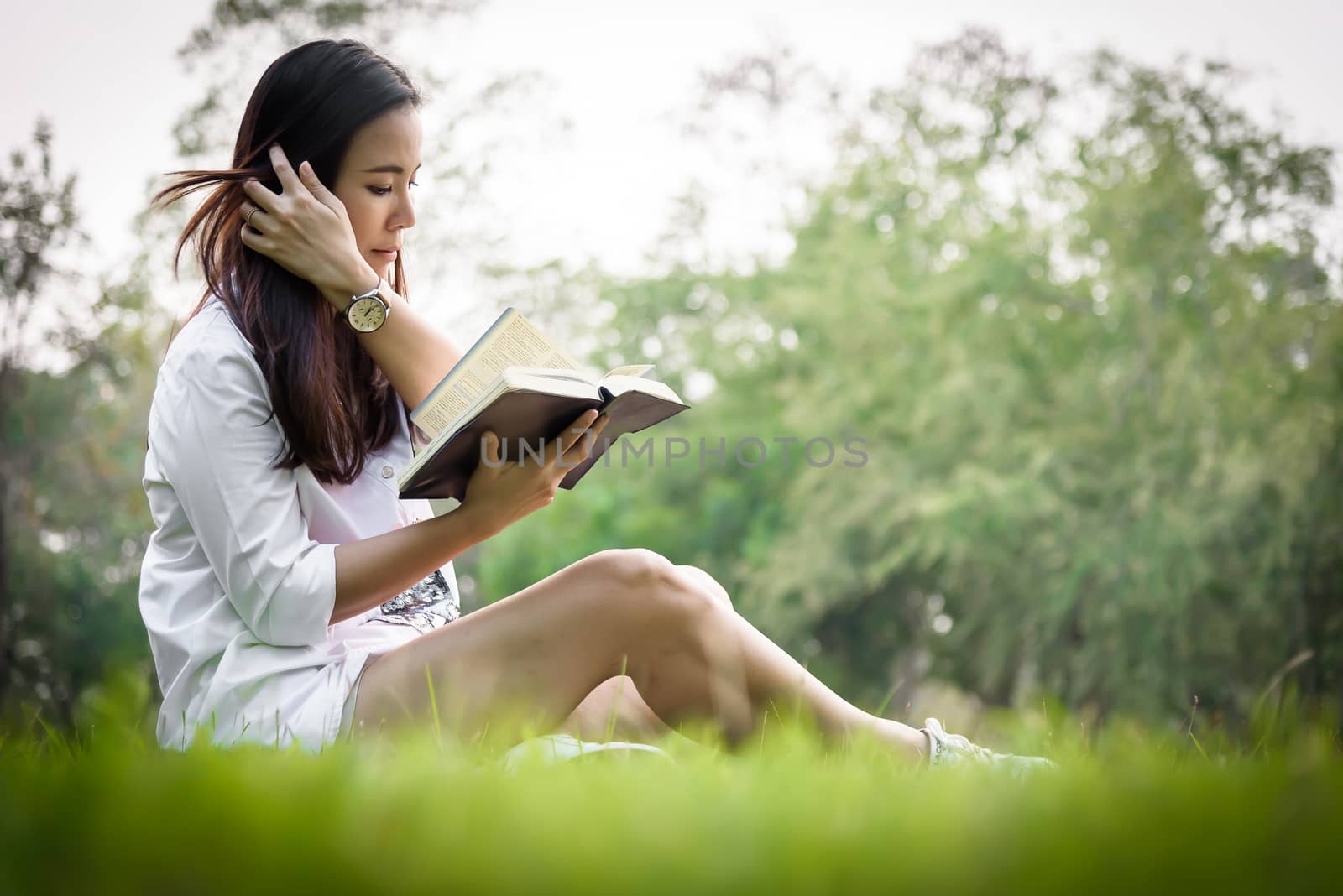 Beautiful asian woman reading a book at garden with happiness an by animagesdesign