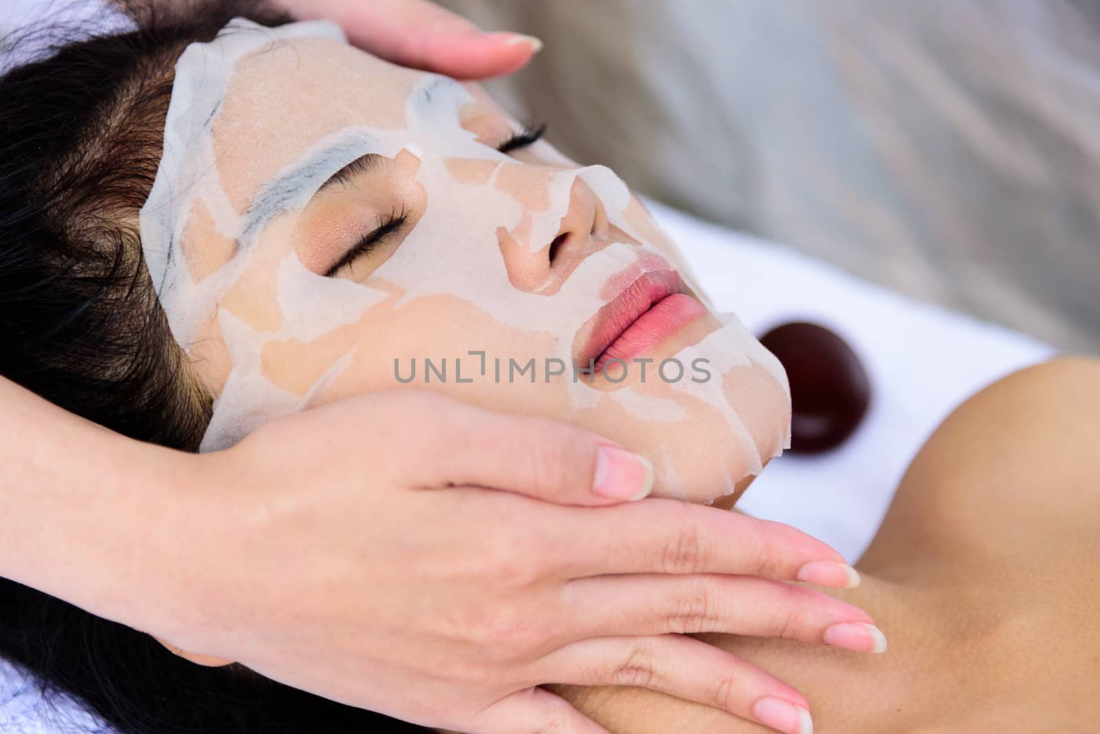 Portrait of beautiful asian people has masking with close up view and close up eyes and having hand massage in spa salon. Beauty, healthy, spa and relaxation concept.