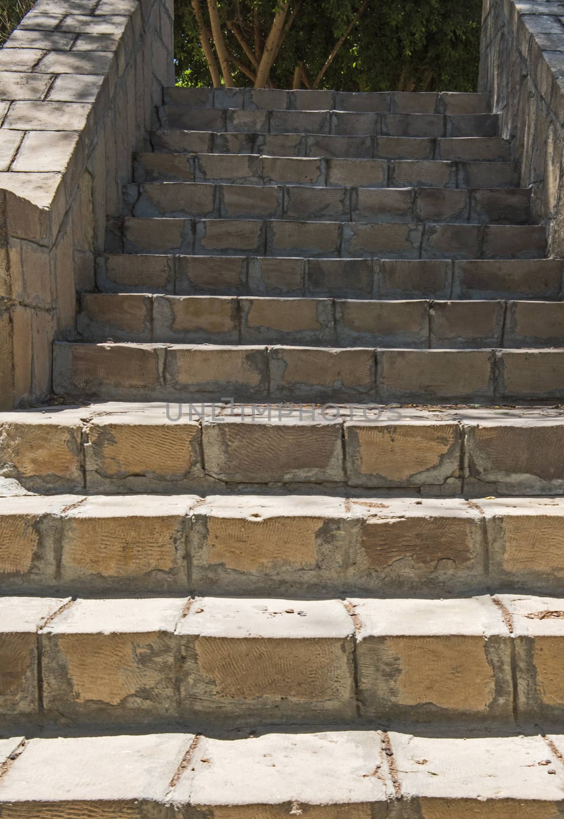 Closeup detail of stone paved steps on rural footpath walkway going upwards in formal garden grounds