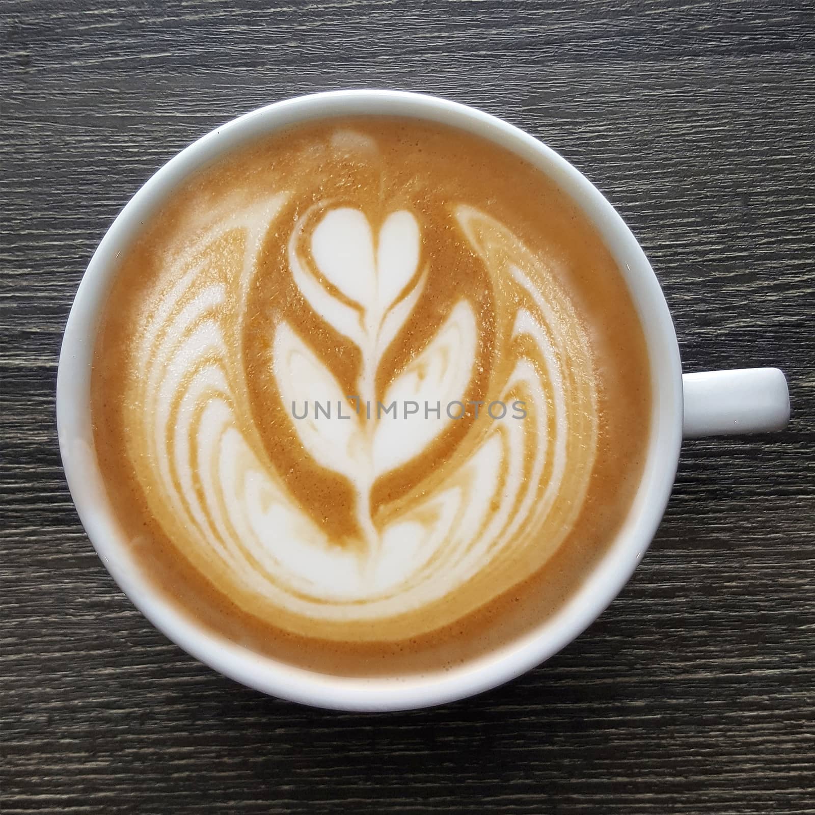 Top view of a mug of latte art coffee on timber background.