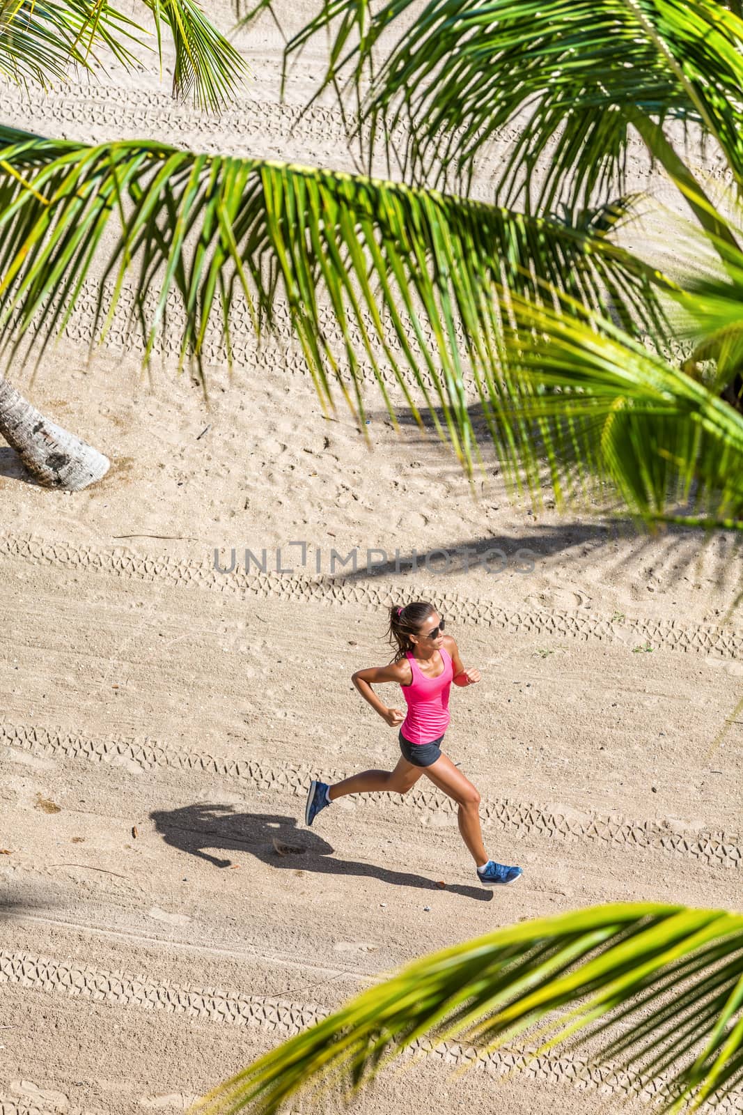 Healthy active life sport woman running training cardio on tropical beach in between palm trees. View from above. Health and fitness concept by Maridav