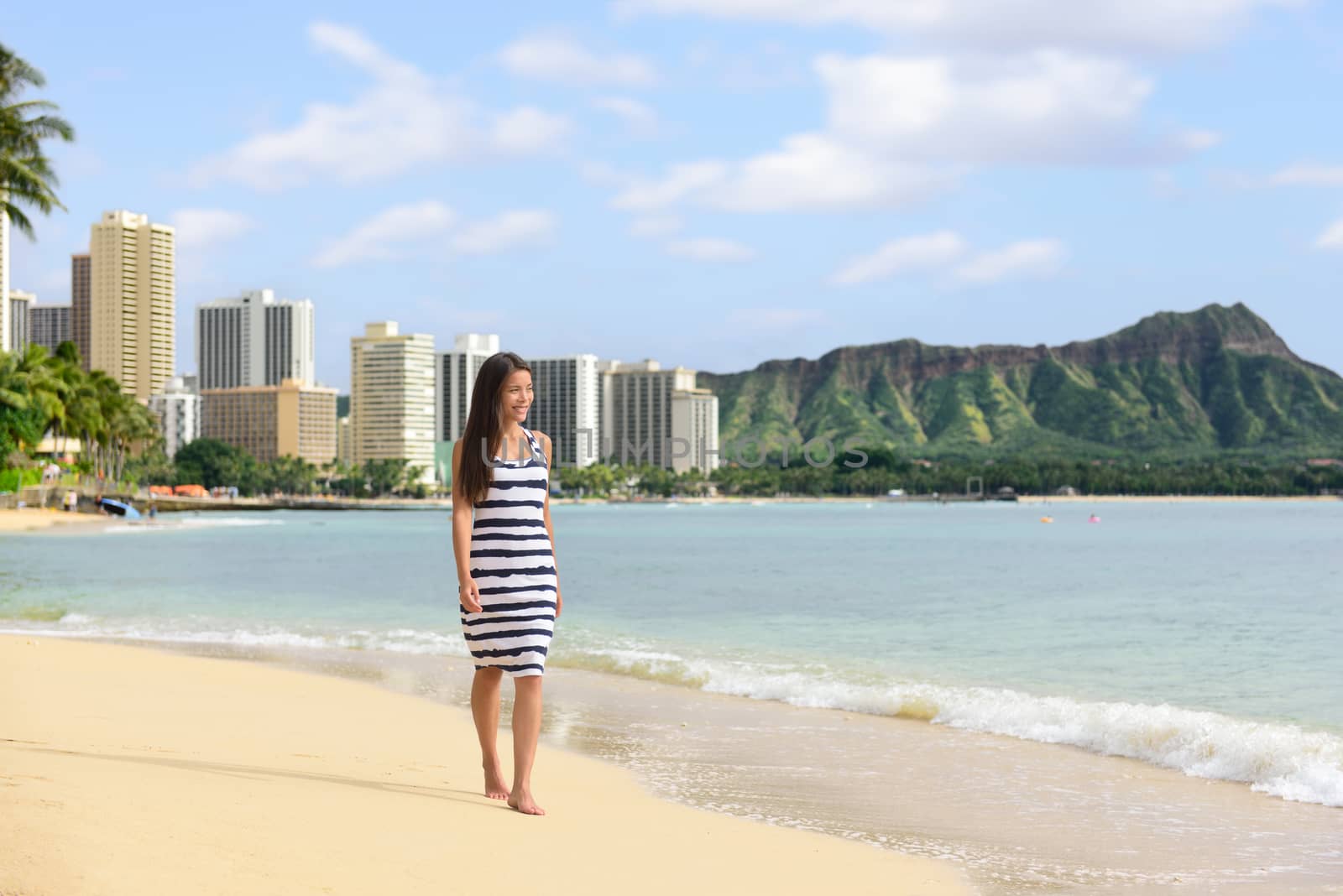 Waikiki beach Hawaii travel tourist woman relaxing walking on sand at sunset on famous beach stretch in Honolulu summer vacation destination in Oahu, Hawaii, USA.