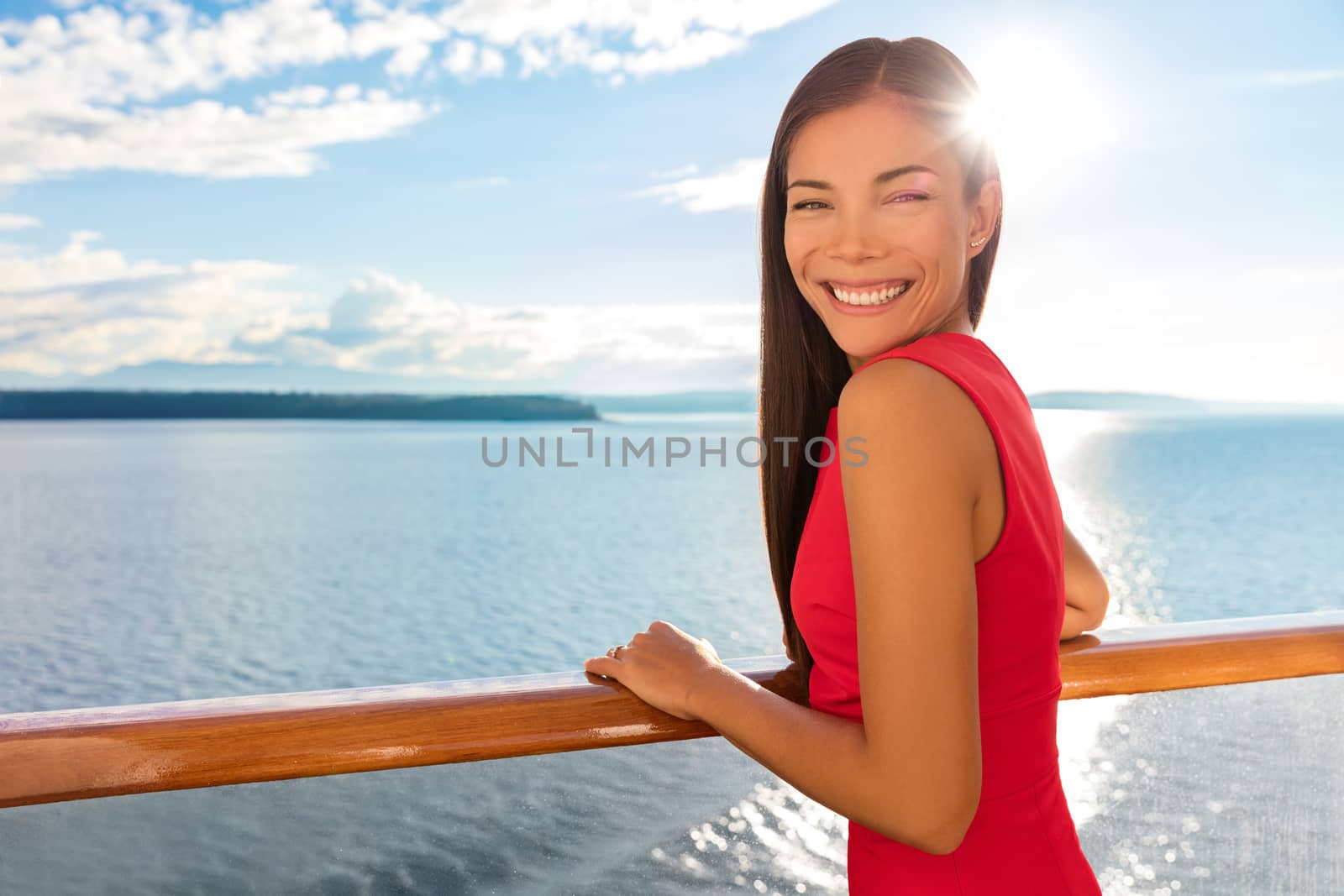 Happy cruise ship passenger outside on suite balcony enjoying luxury view of ocean in travel destination during summer. Beautiful Asian woman.