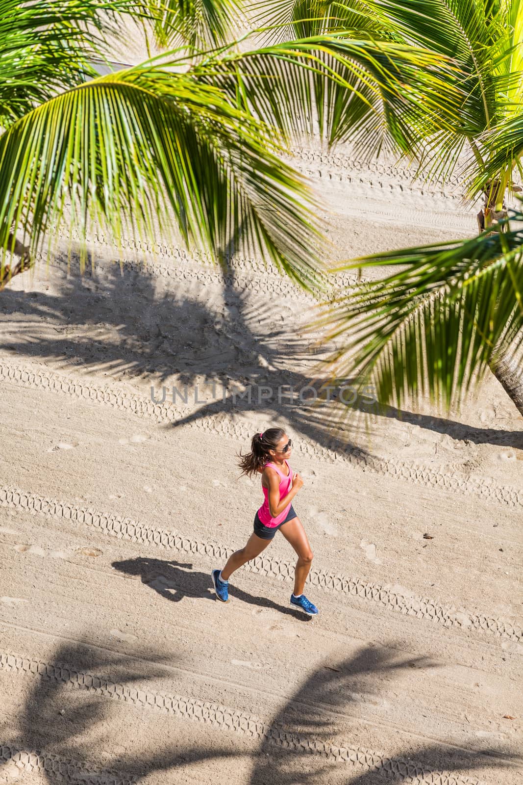 Healthy active lifestyle sport woman running doing exercise workout on tropical beach in between palm trees. View from above of the ground and sand. Health and fitness concept by Maridav